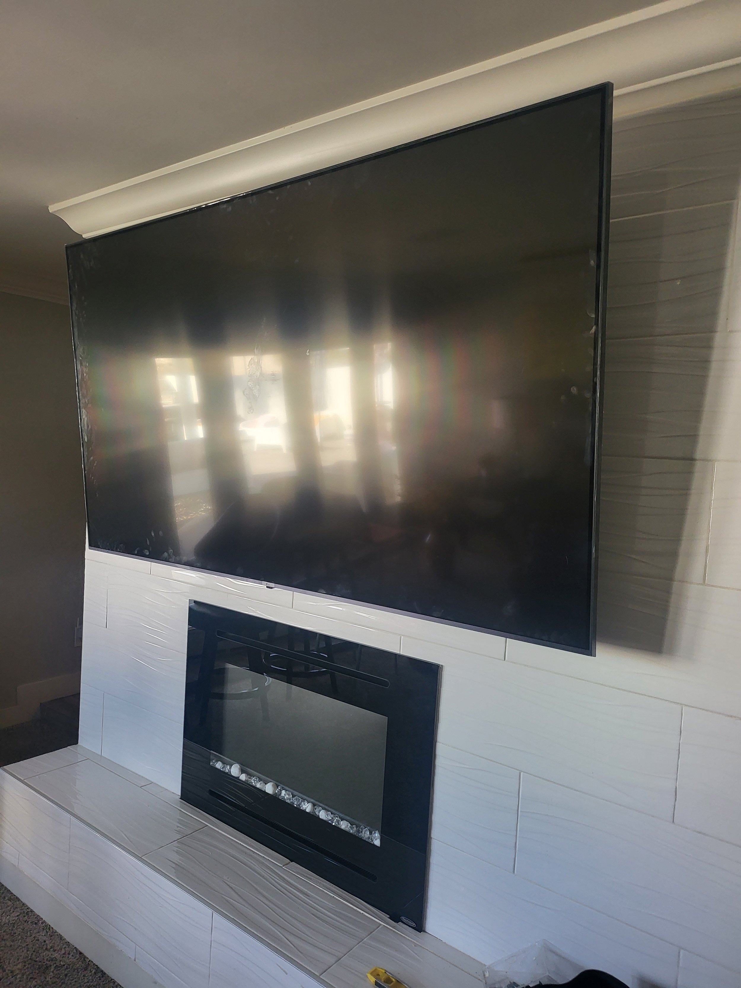 Professional living room TV wall mounting in Phoenix, AZ, positioned perfectly above a wooden media console with full in-wall wire concealment and stud-anchored wall brackets.