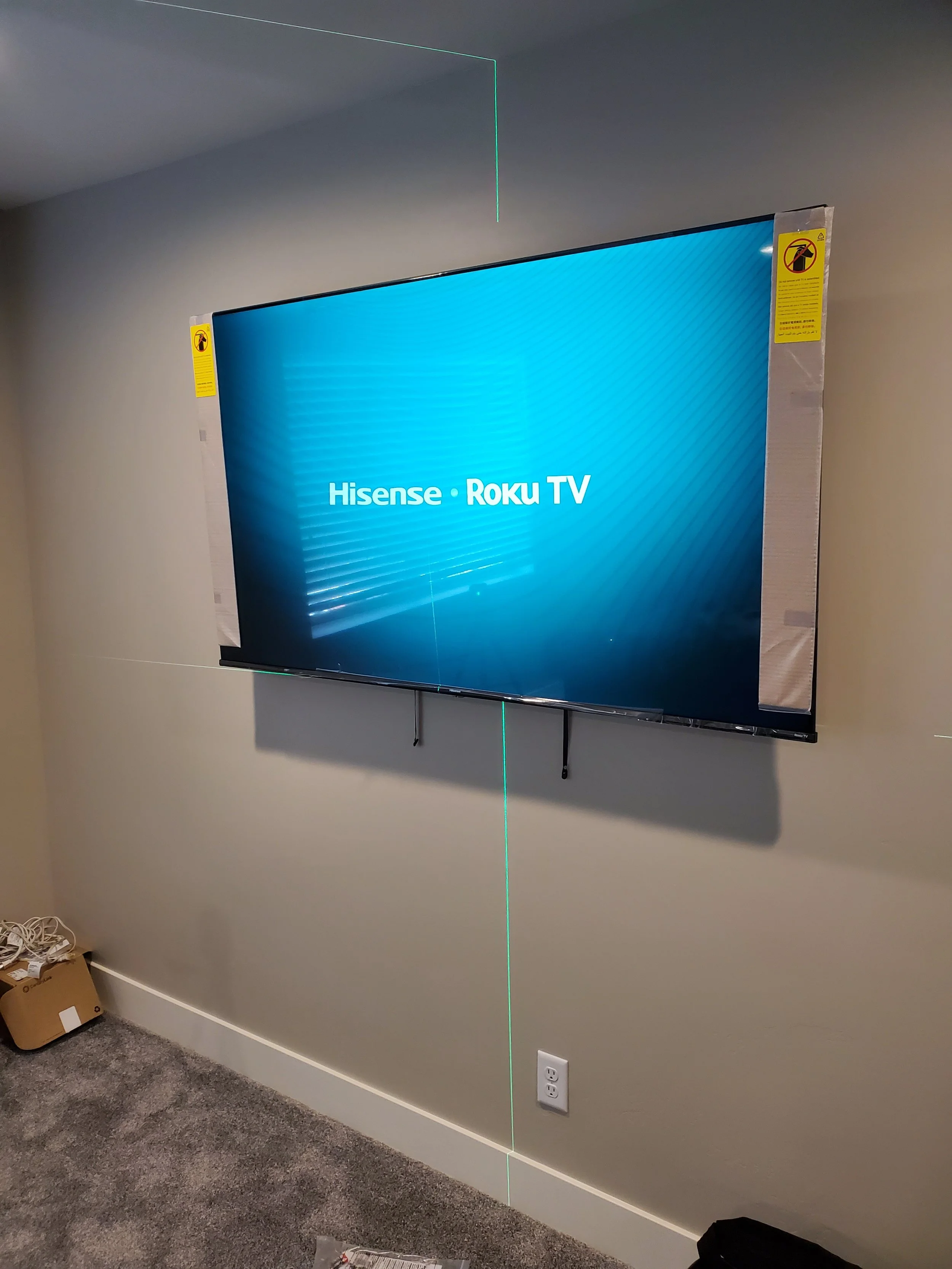 Precision laser-leveled commercial TV installation in a Phoenix industrial workspace, featuring high-elevation ladder access, heavy-duty wall anchors, and laser-guided alignment.