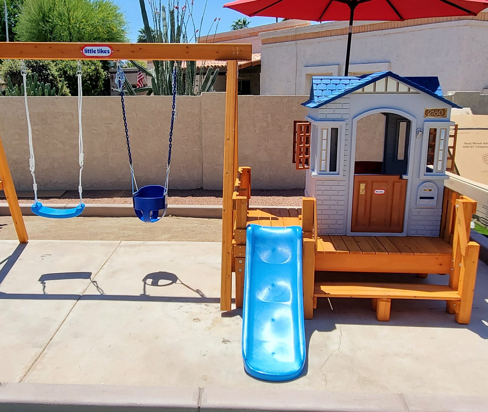 Little Tikes cottage playhouse with A-frame swing set and slide assembled in a Scottsdale backyard