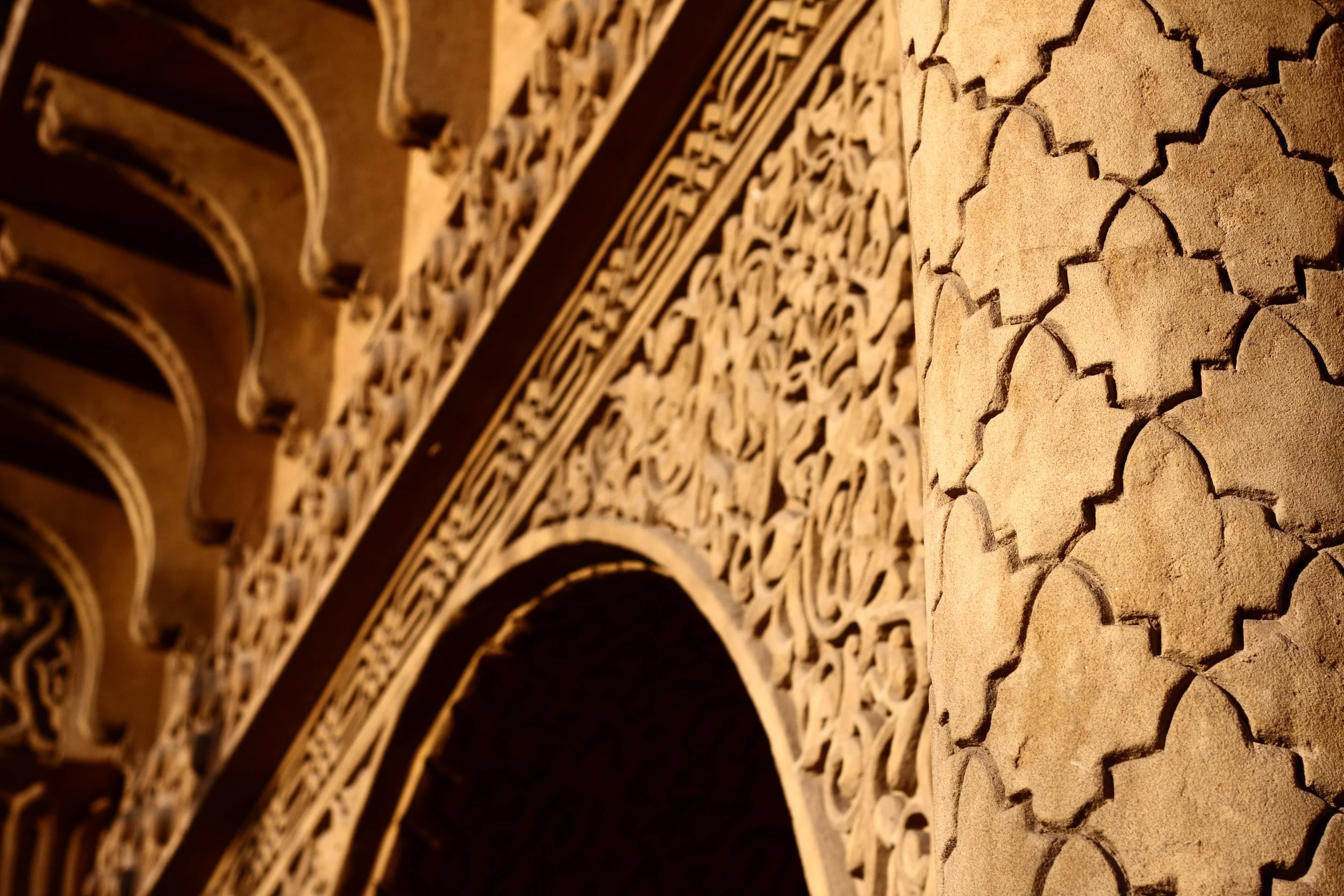 Close-up of intricate hand-carved stucco and traditional geometric arches in a luxury Moroccan riad.