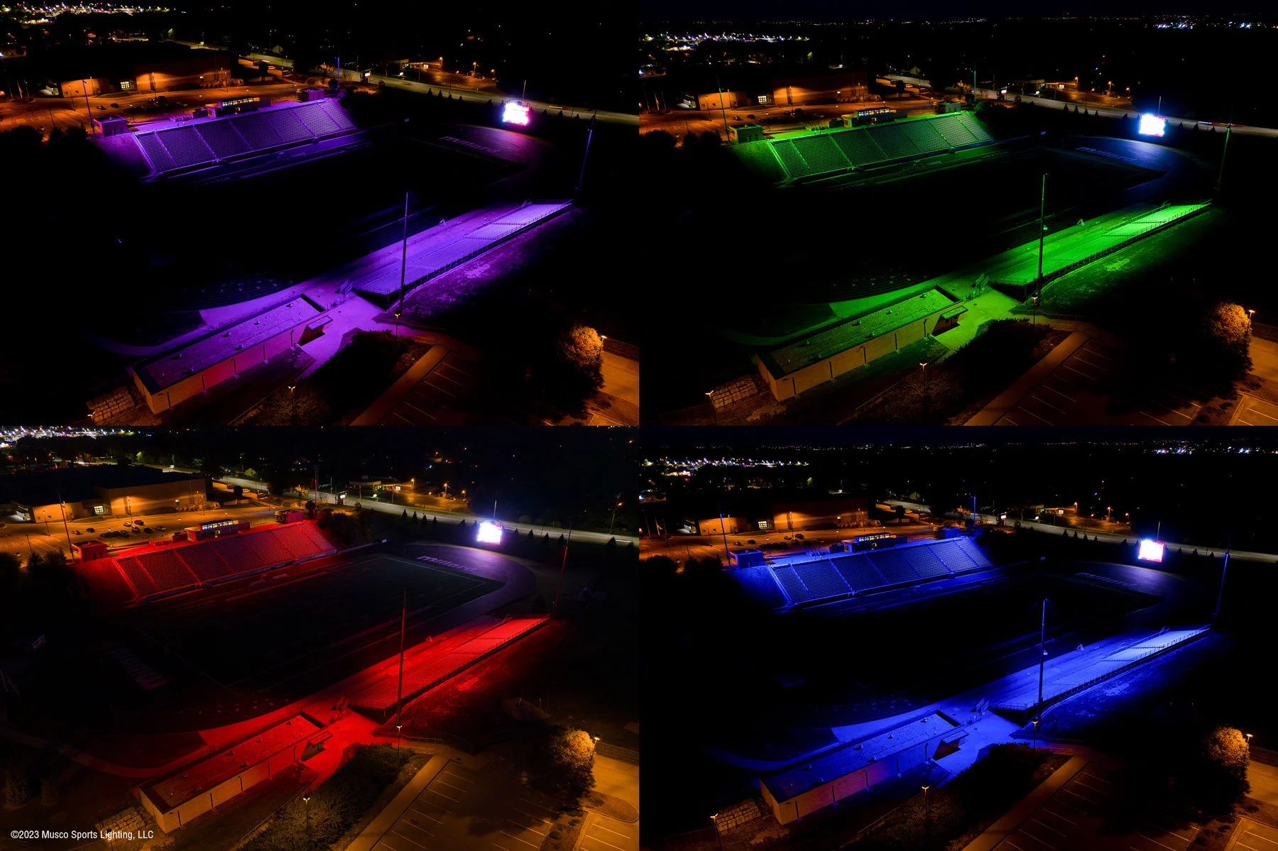 Aerial view of a stadium at night, illuminated with different colored lights: purple, green, red, and blue in four quadrants.