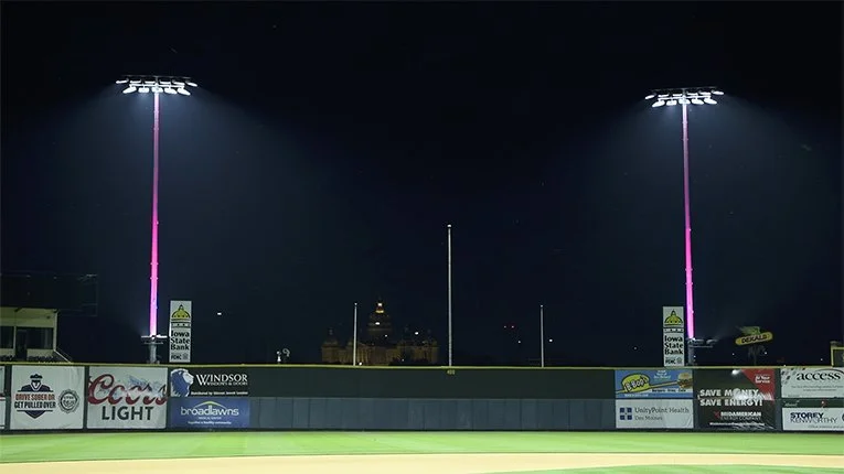Nighttime view of a baseball stadium with tall bright stadium lights and a dark sky in the background.