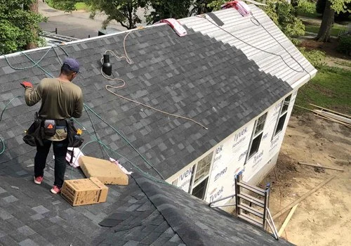 Construction worker installing or repairing a roof on a house in a residential area.