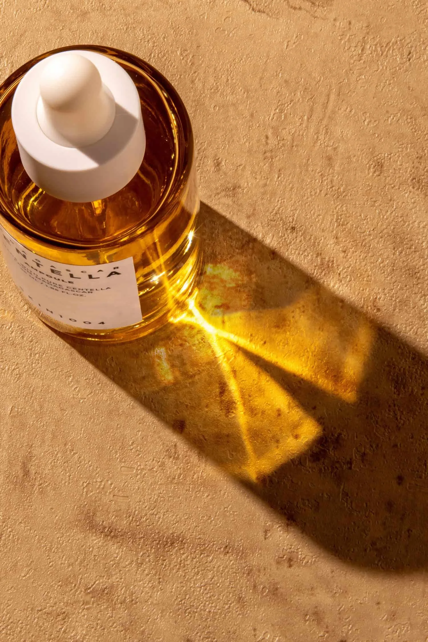 Closeup up of light rays shining through a bottle of Centella facial serum