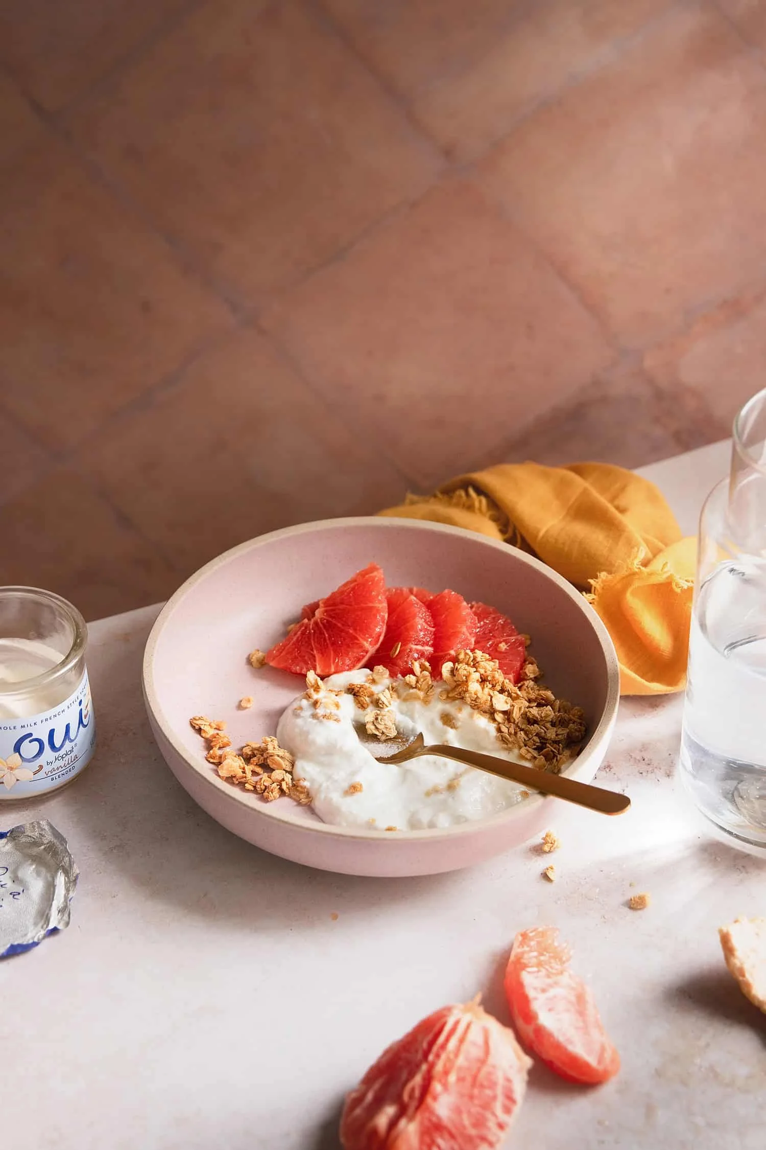 A bright breakfast scene featuring yogurt topped with granola and grapefruit