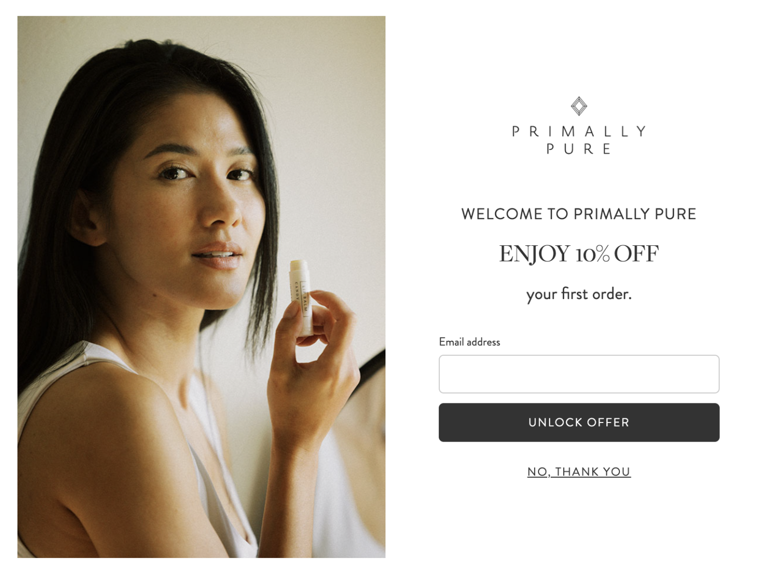 An image of a woman holding lip balm and looking at the camera