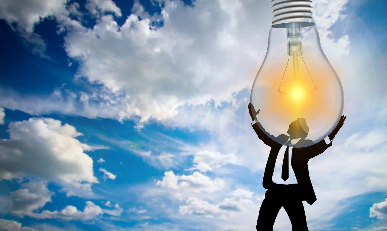 A image of a guy in a suit grabbing a light bulb in the sky - life and career coach Phoenix