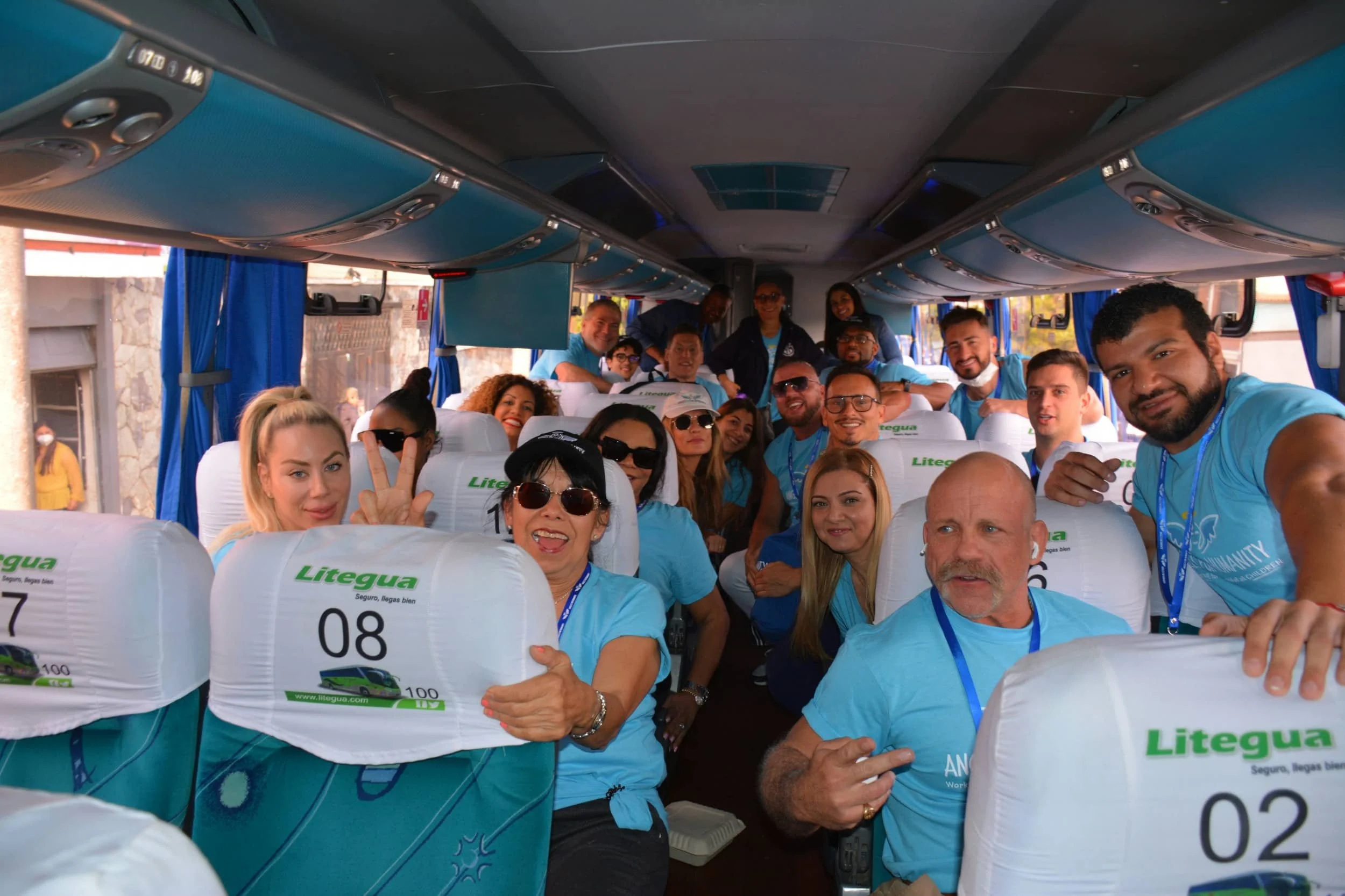 A bunch of women and men on a bus wearing blue shirts and smiling - multi-dimensional life