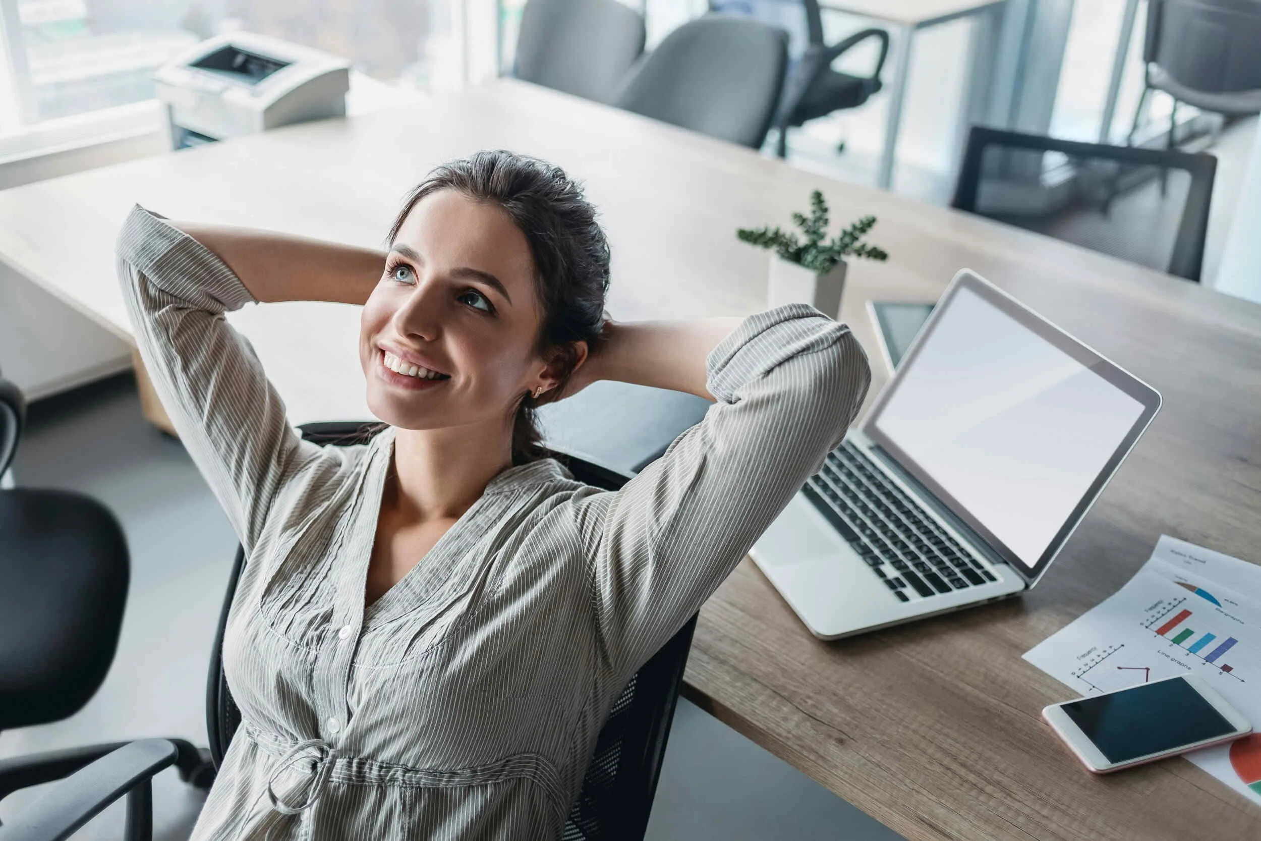A women inside an office in a chair smiling with her hands behind her head - how to get unstuck in your career
