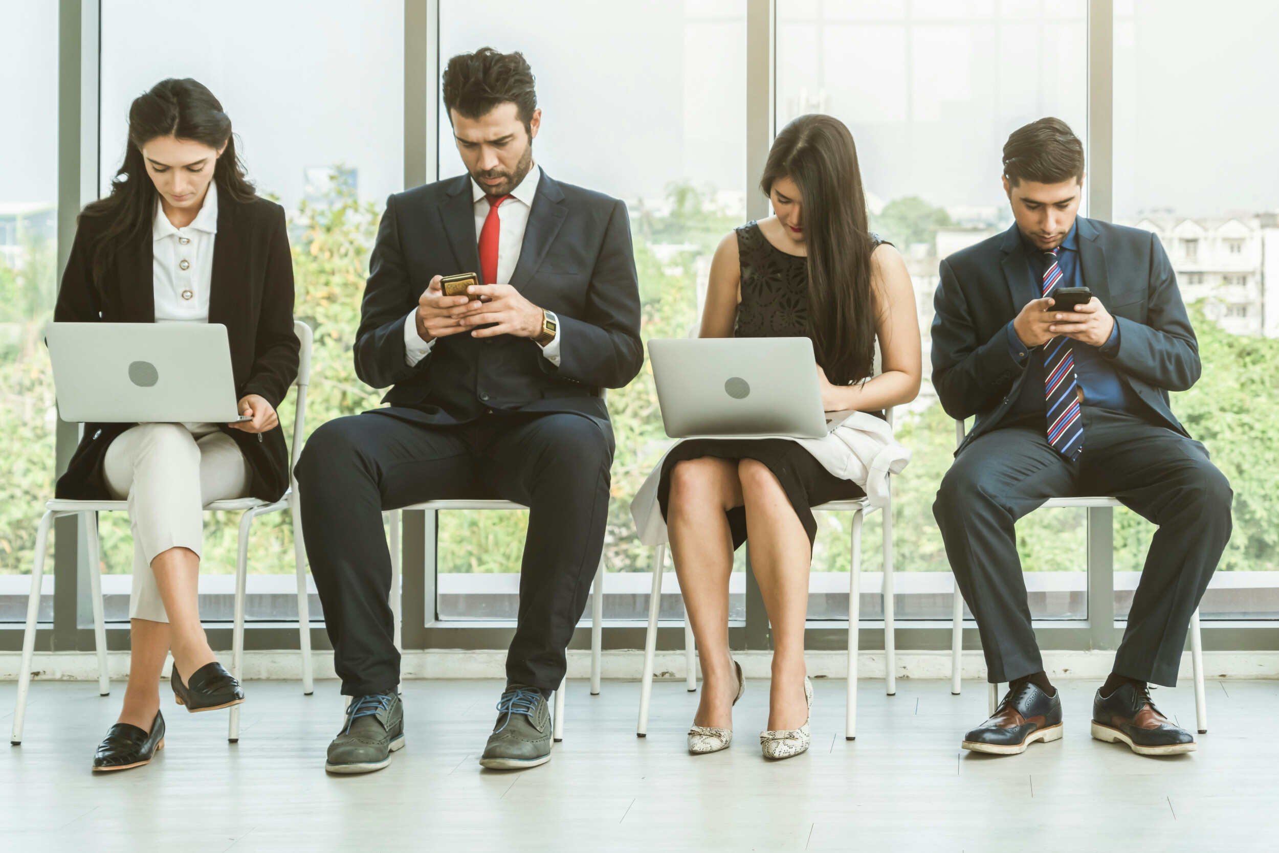 A man and women sitting in chairs looking at their computer and phones inside - job search help Phoenix