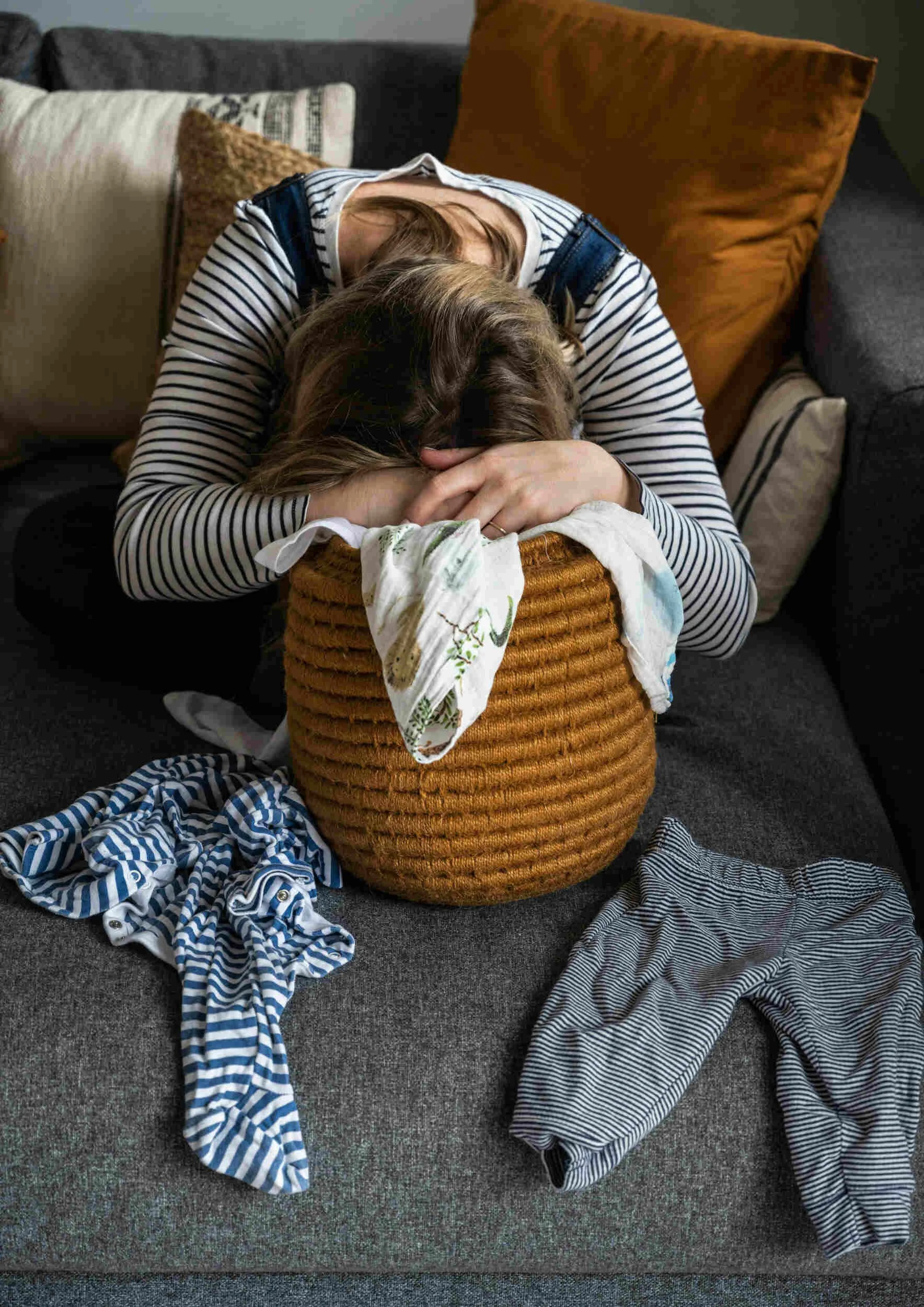 A women exhausted has her head in a laundry basket with clothes everywhere - how to get out of a rut