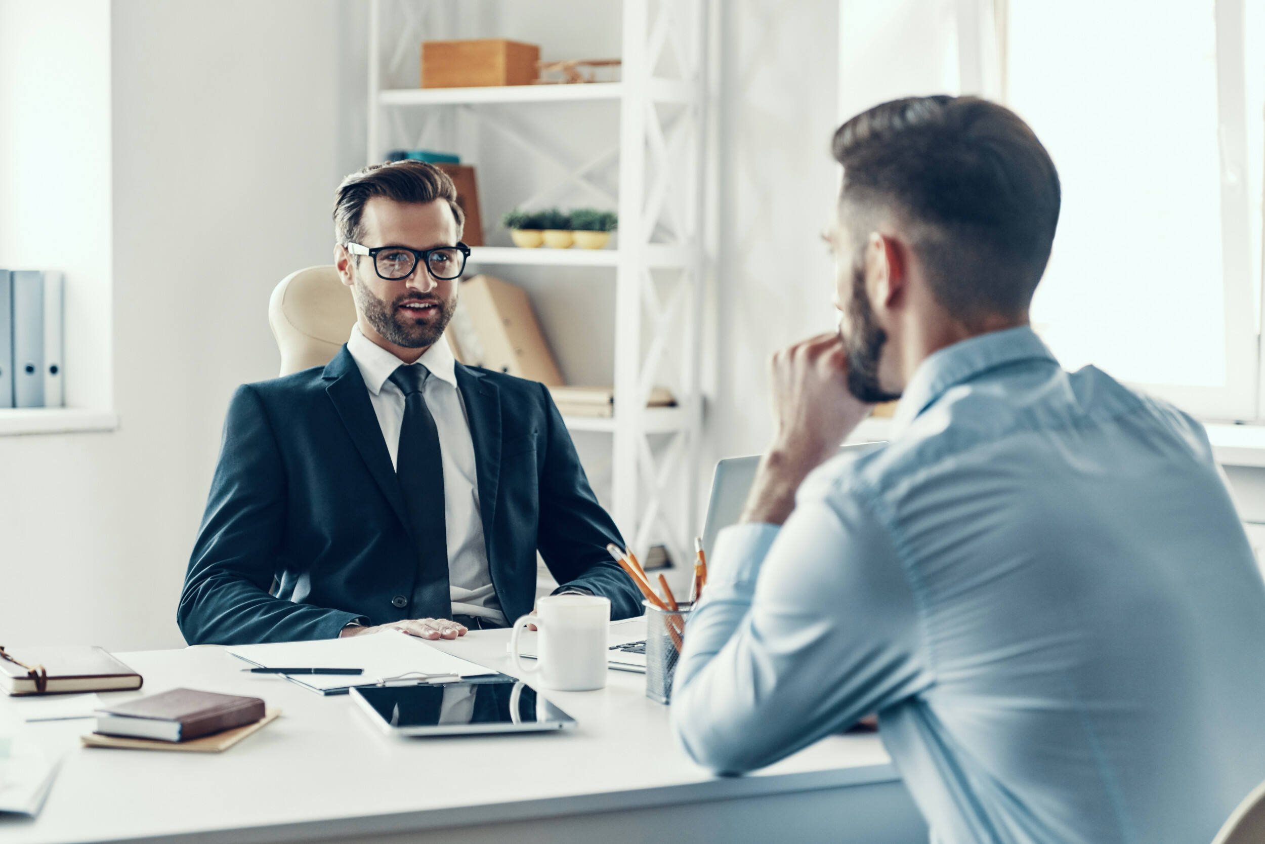 Two well dressed men sitting at a table inside - what is executive coaching