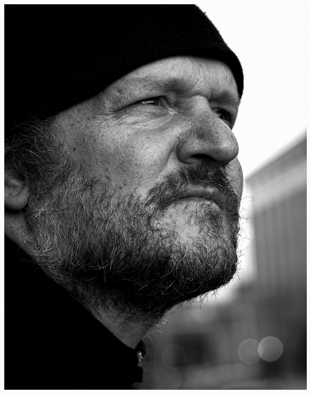 A man with a black beanie hat and a beard staring in the distance - multi-dimensional life