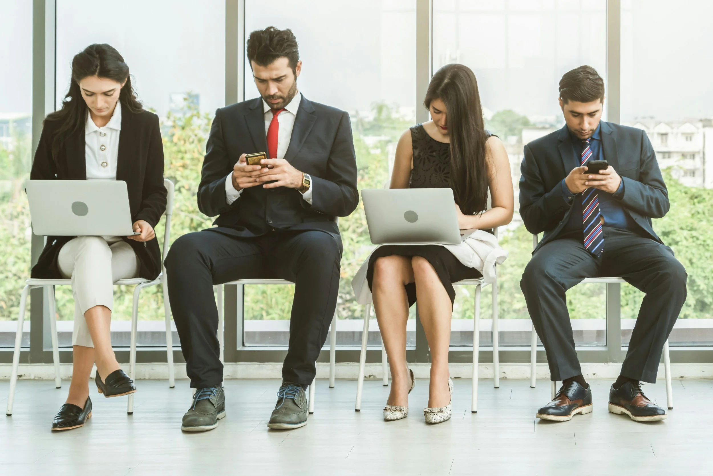 Four people on their computers and phones while sitting inside - recruiter asked for current salary