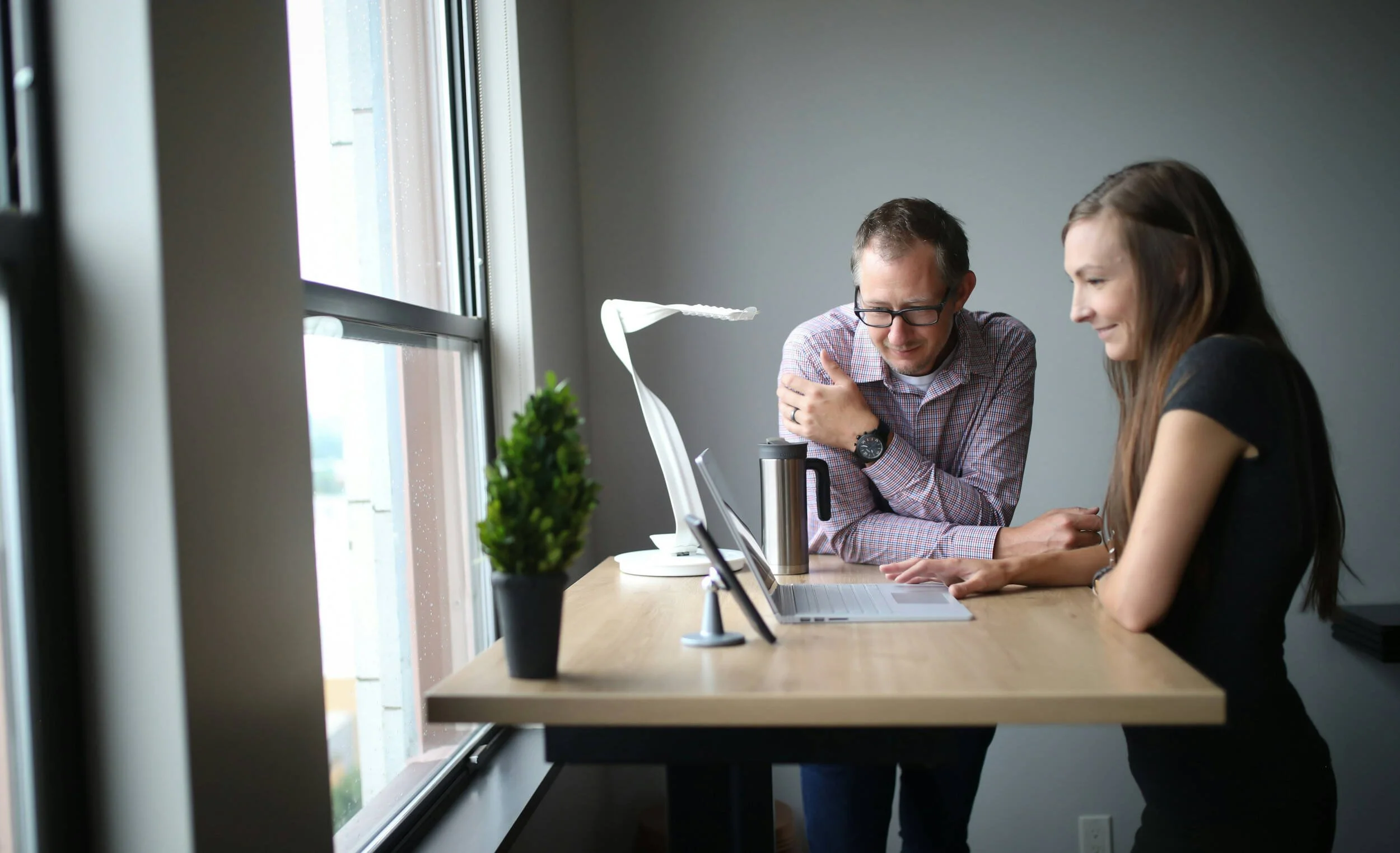An older man and young woman in front of a laptop at a desk inside - career coaching for young adults Phoenix