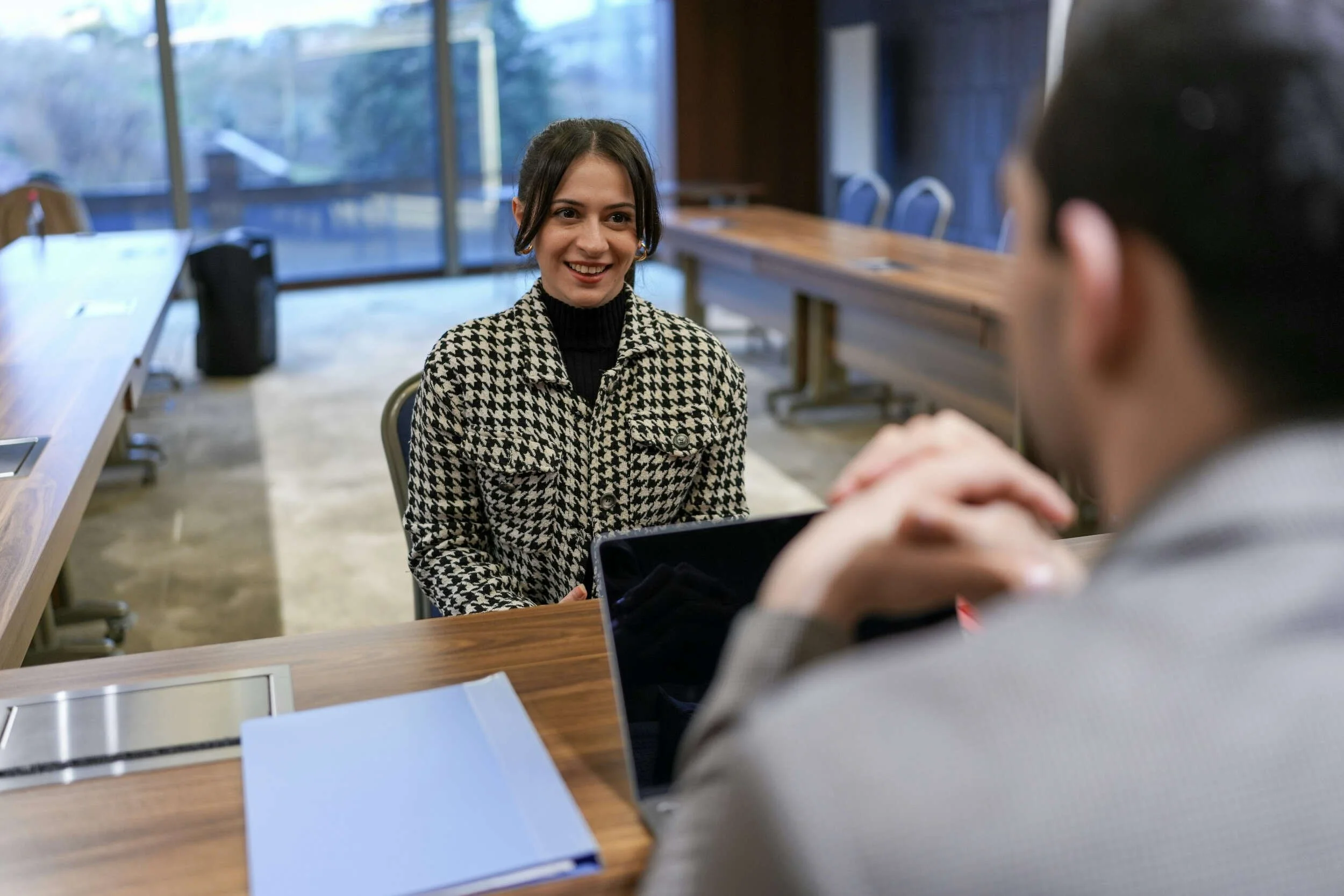 A man and woman sitting at a table for an interview inside - Using AI To Prepare For Interviews