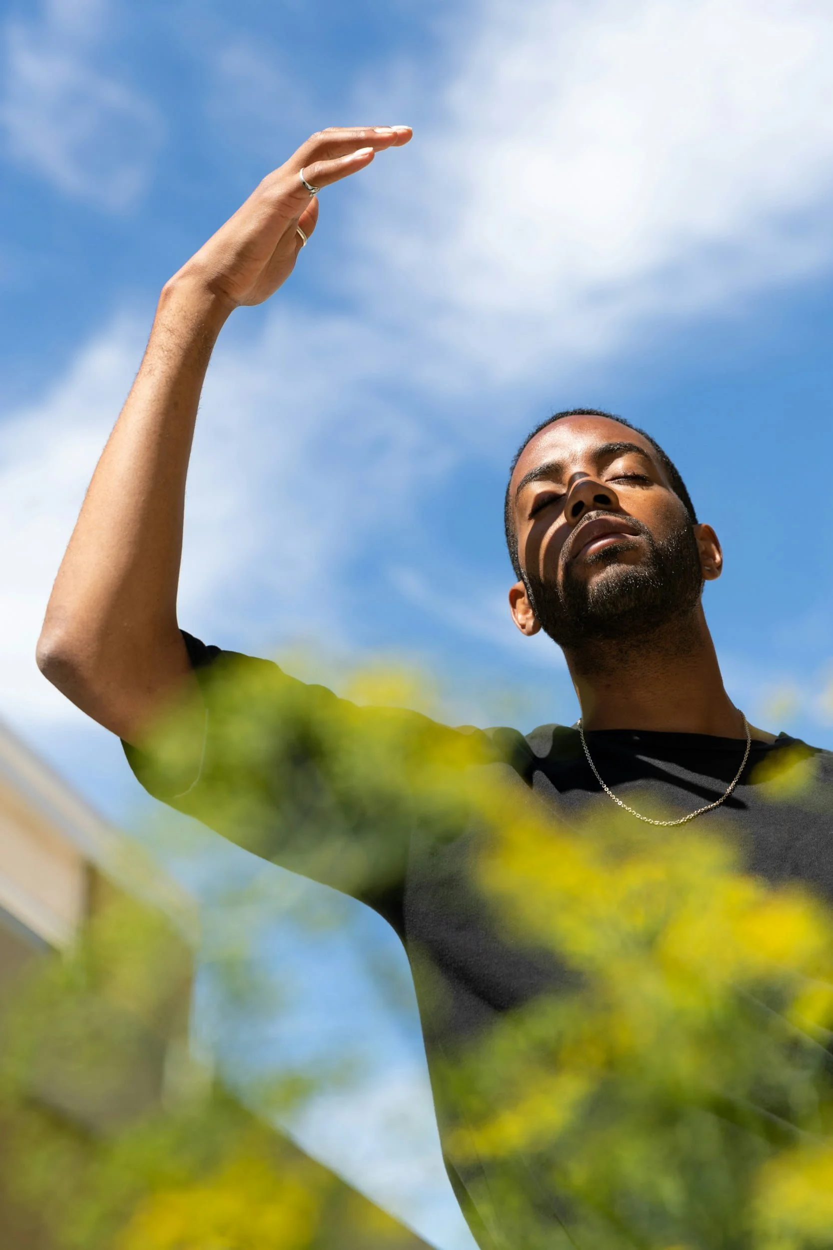 black man outside with his eyes closed, hand in the air, and sun on his face - Job burnout what to do