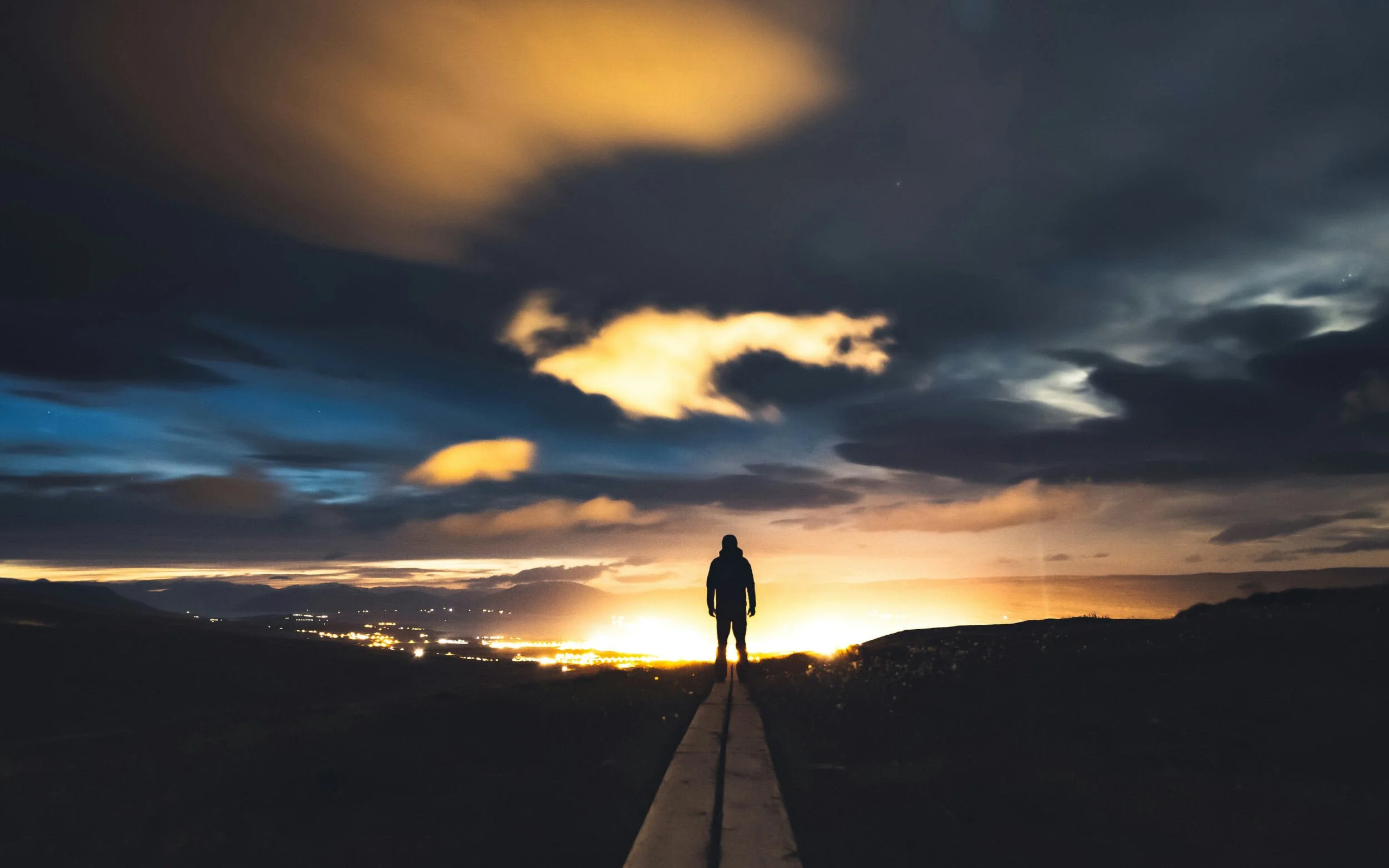 Man standing outside overlooking city lights with clouds above at sunset - career transition coach Scottsdale