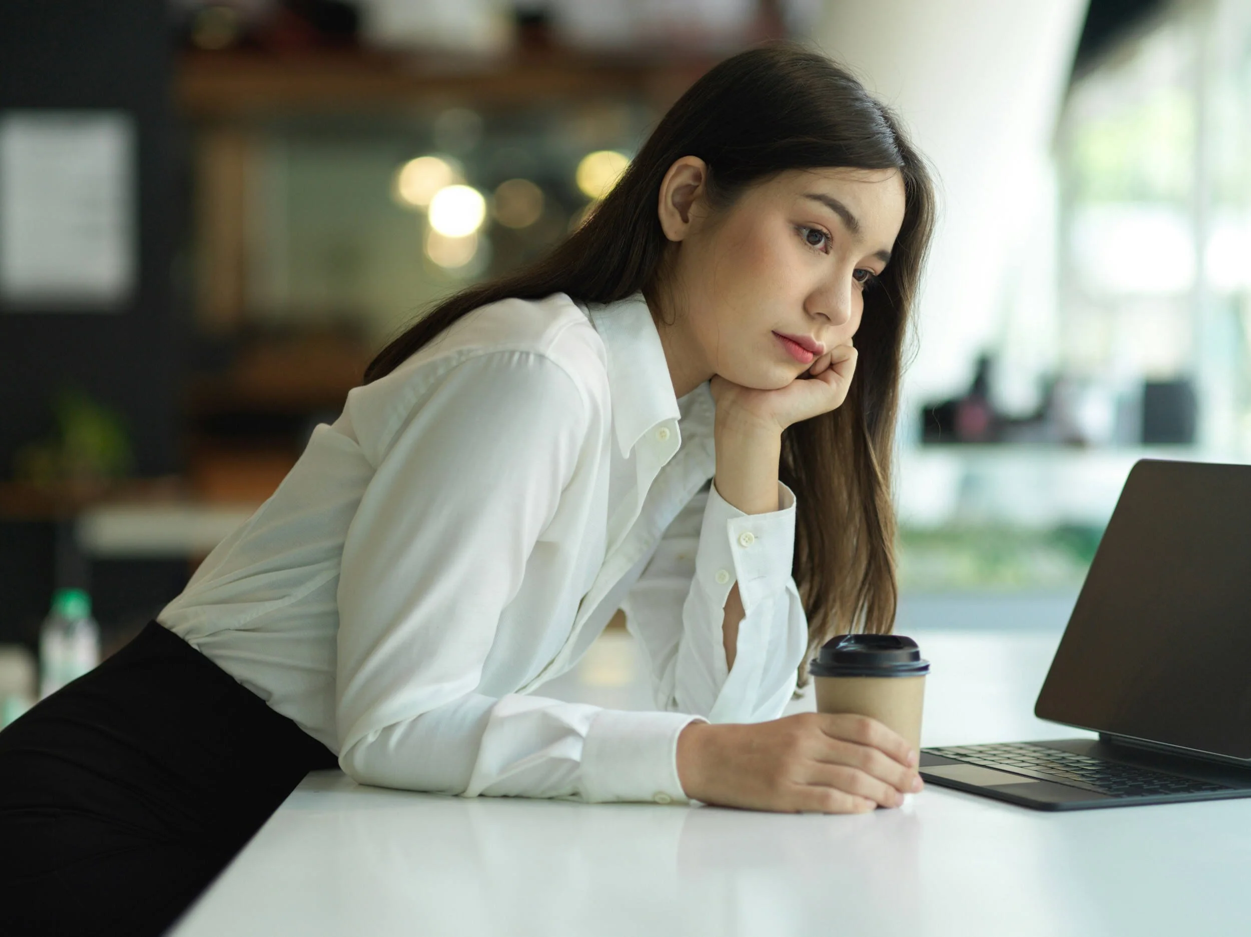A women with dark hair in an outfit at work looking sad - successful but unfulfilled