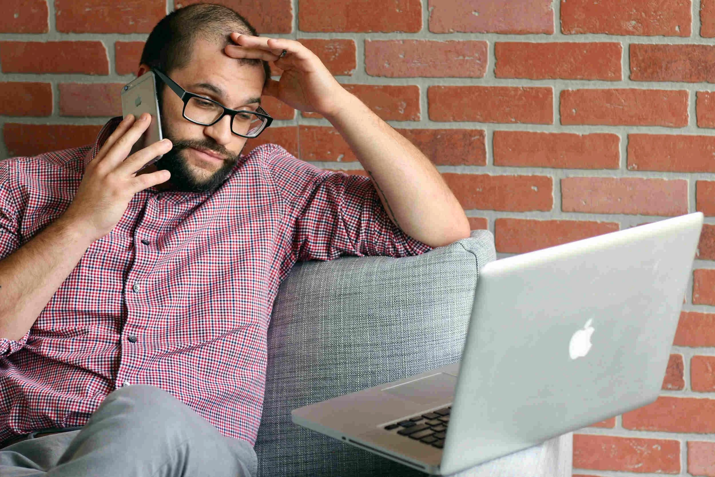 A man on a phone looking at his computer frustrated - overqualified for a job
