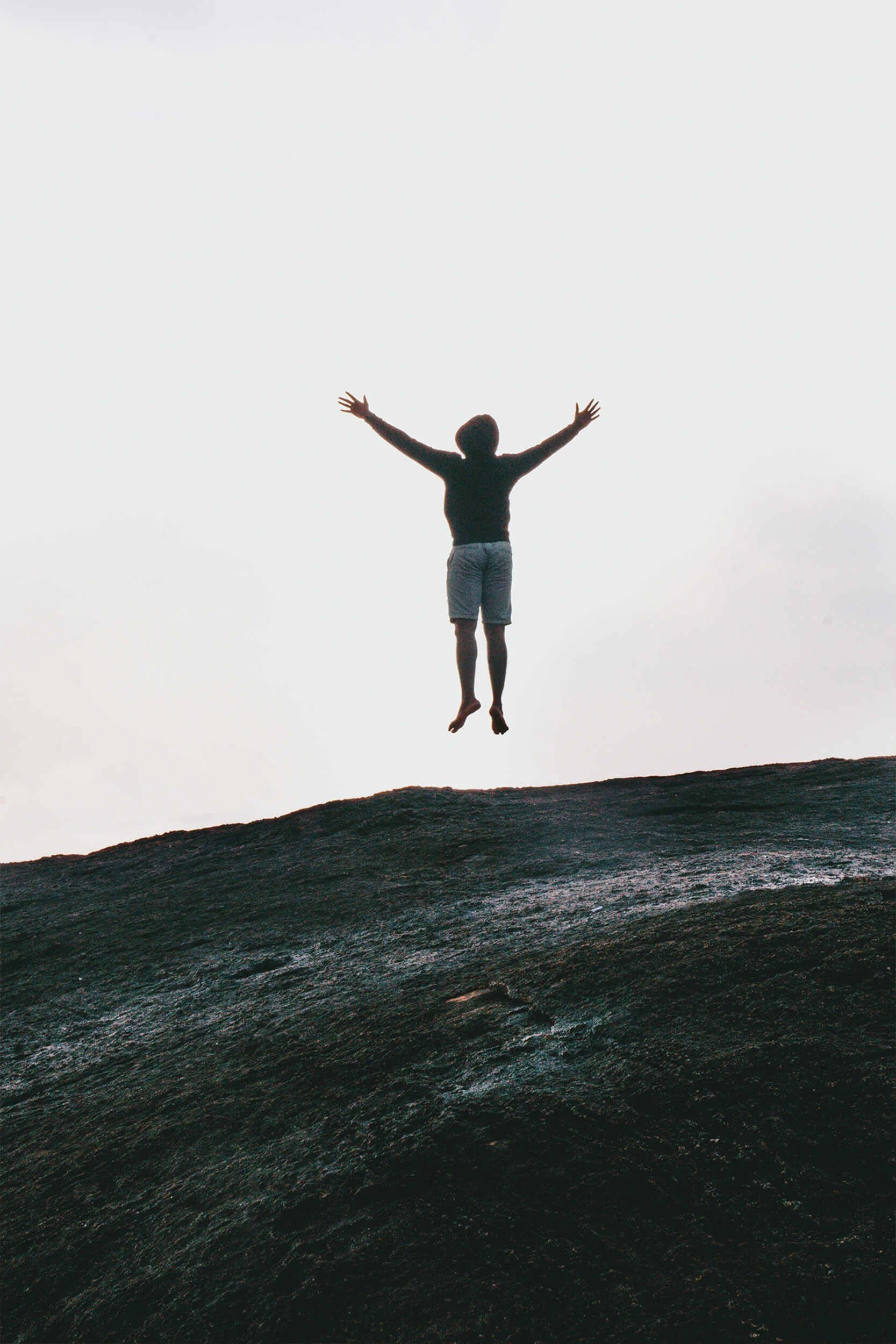 A man jumping up in the air with his arms out outside - career coach