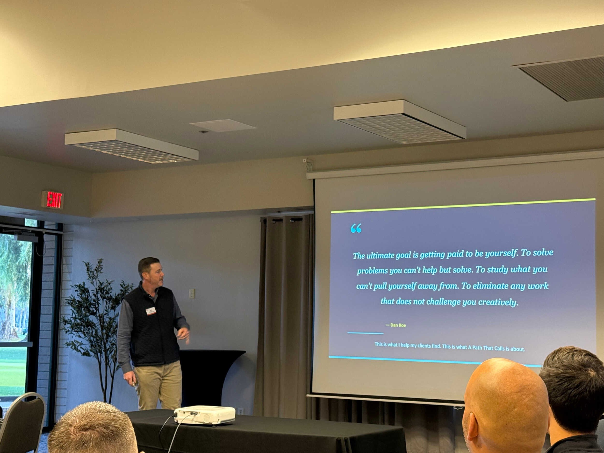 A man presenting inside reading a quote to an audience - career pivot from tech to coaching