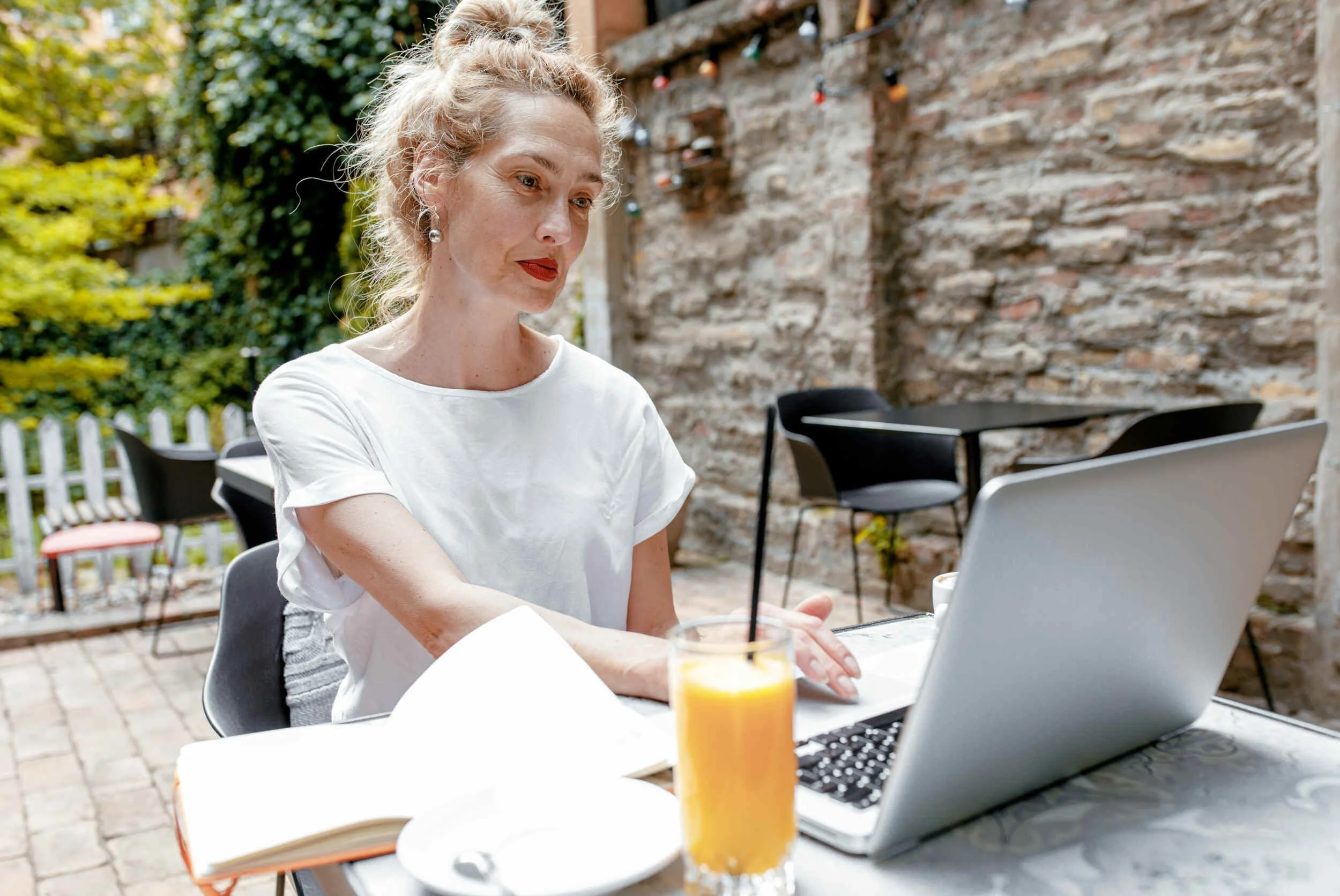 A women outside with her laptop sitting down with orange juice - career coach