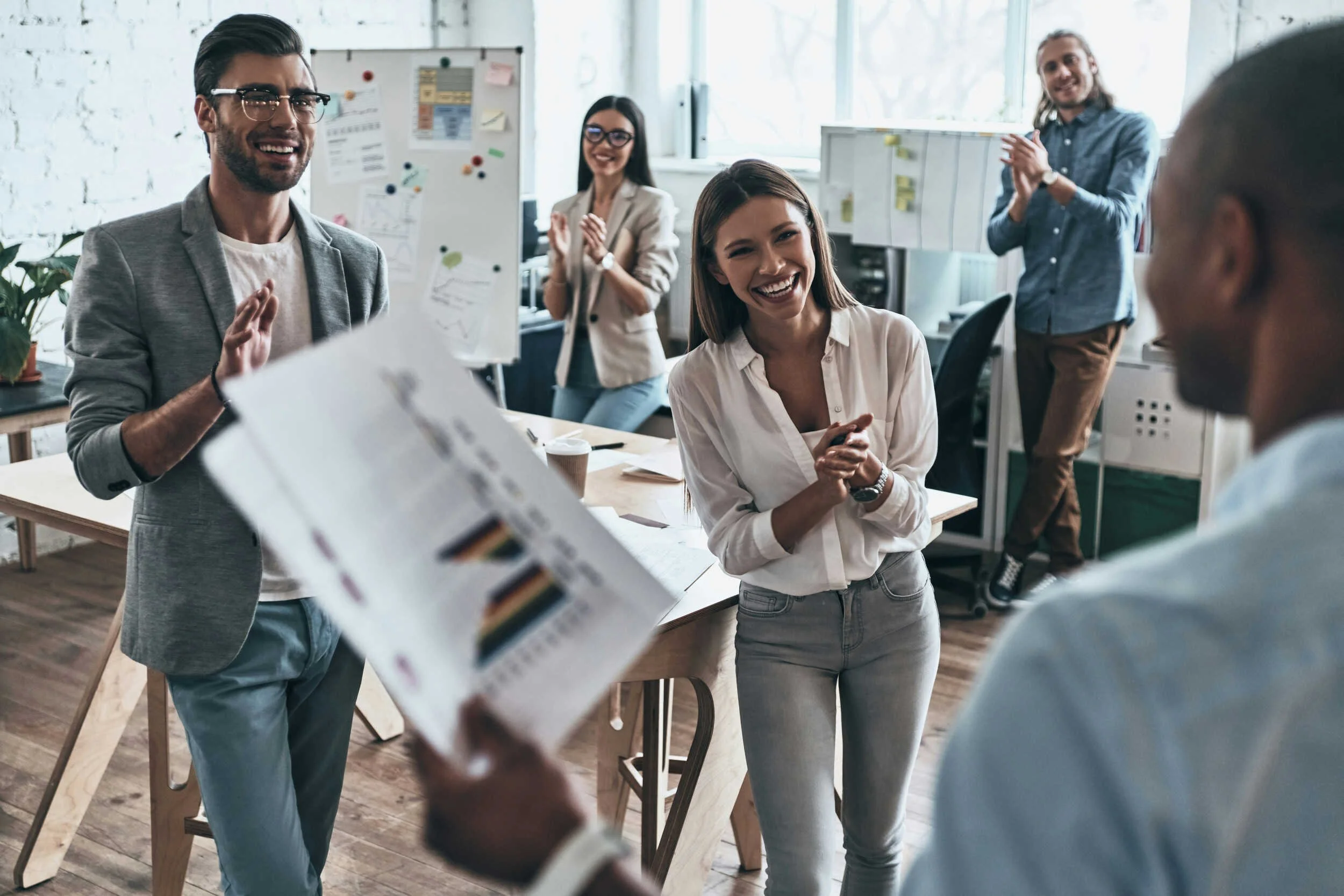 A man presenting news to his team inside and everyone is excited - job search after layoff