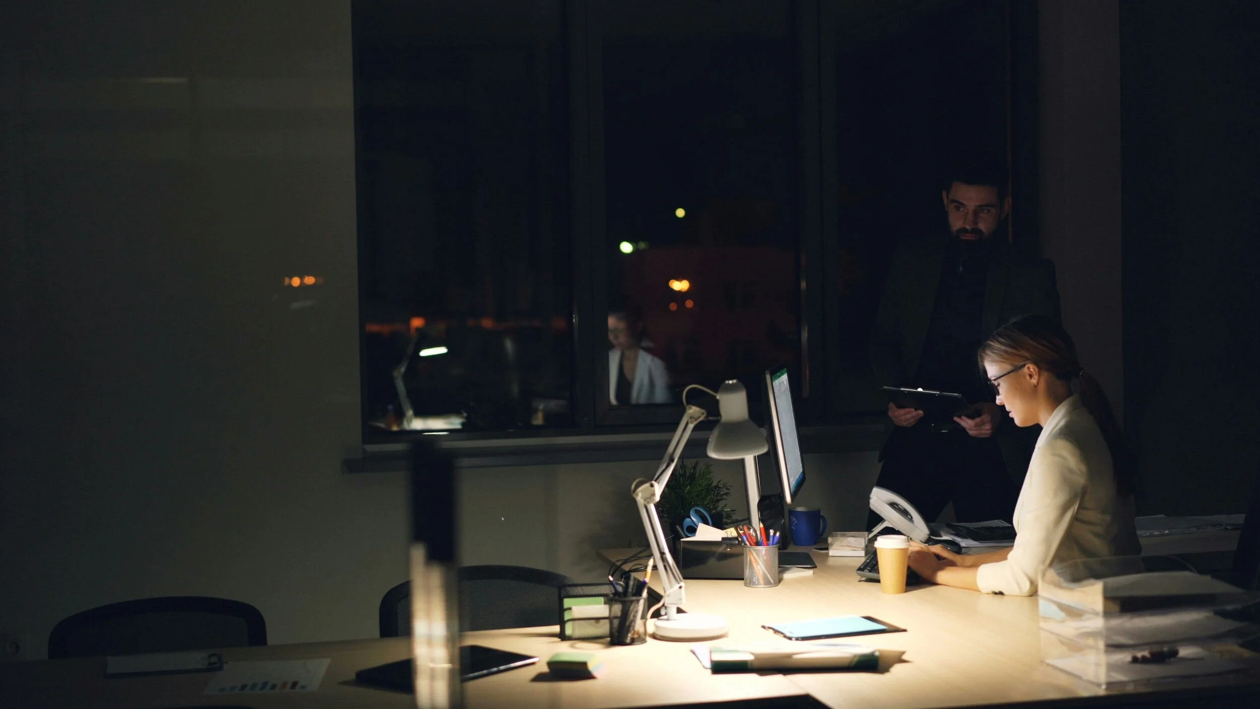 women sitting at her desk with the light on late at night - life and career coach