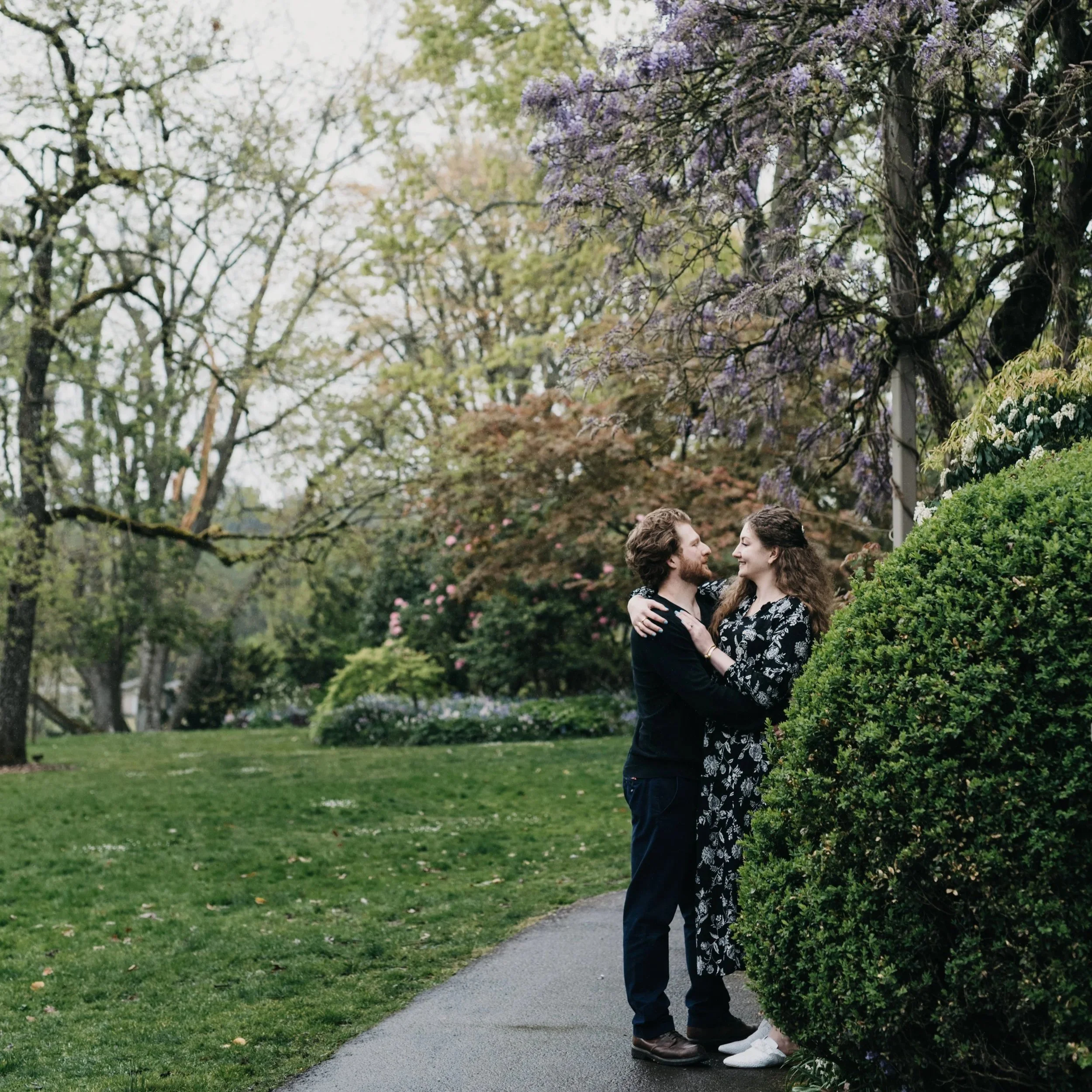 A couple lovingly look at each other in a garden