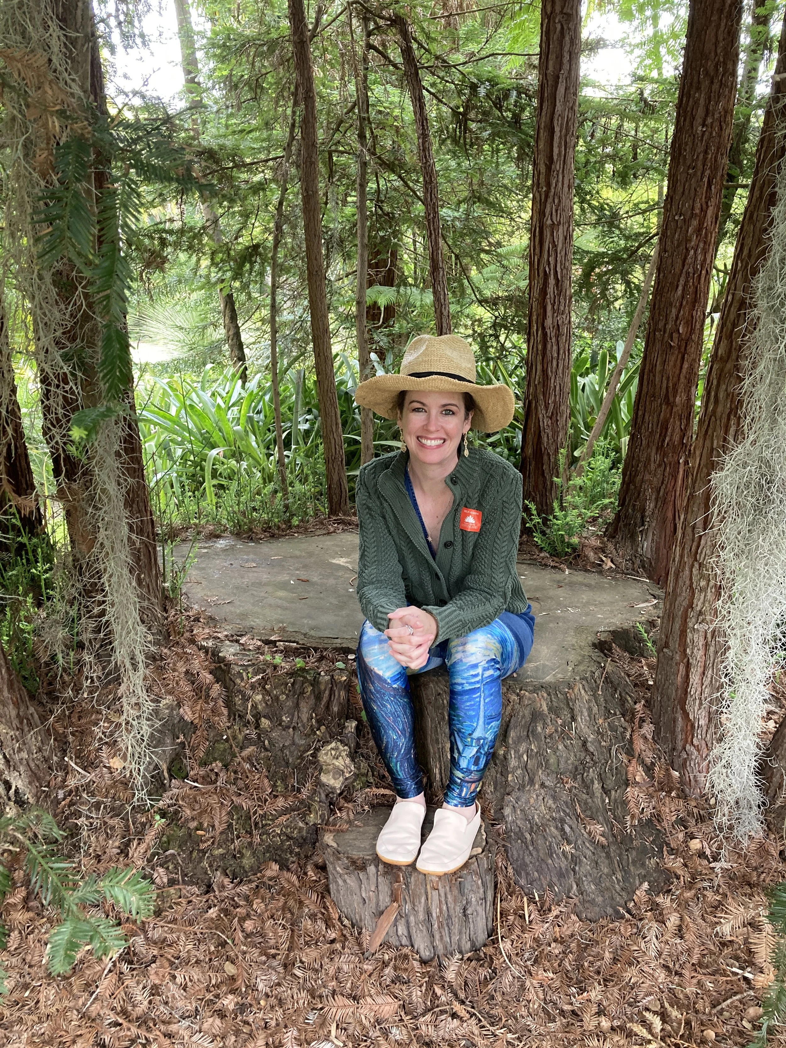 Dani sitting on the stump of a parent tree surrounded by saplings - a "fairy ring"