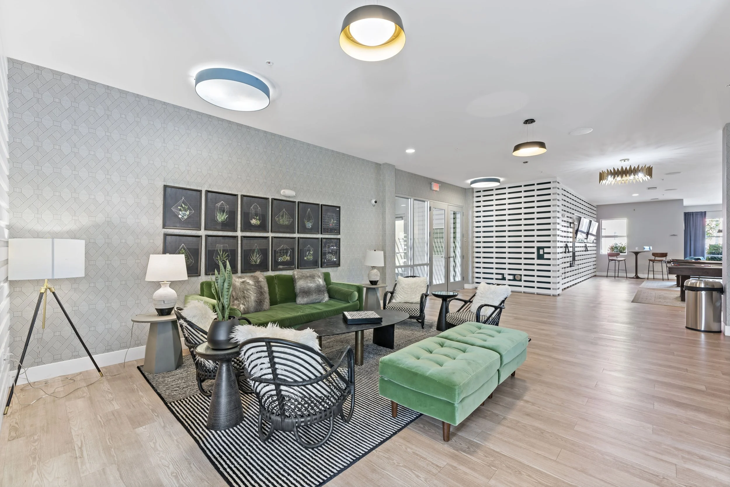 Modern lounge area with green and black furniture, framed artwork, and wooden flooring.