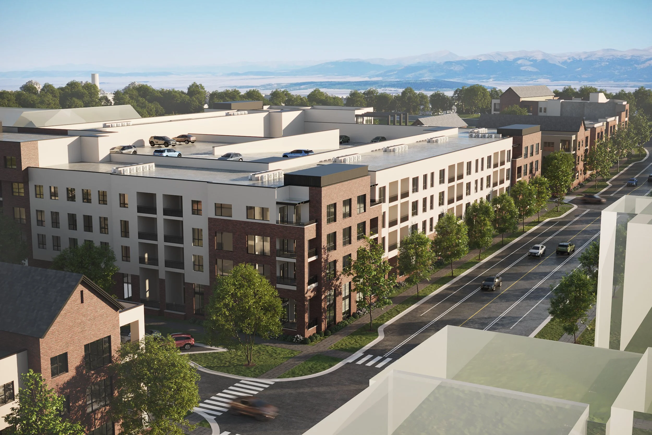 A modern multi-story residential building with a flat roof, surrounded by trees and a street with cars, in a suburban area with mountains in the background.