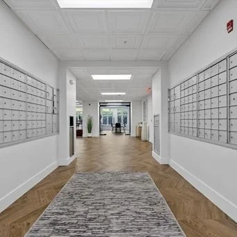 Hallway in an apartment building with mailboxes on each side and a lobby with seating in the background
