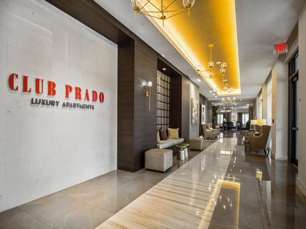 Lobby of Club Prado luxury apartments with seating areas, modern lighting, and stylish decor.