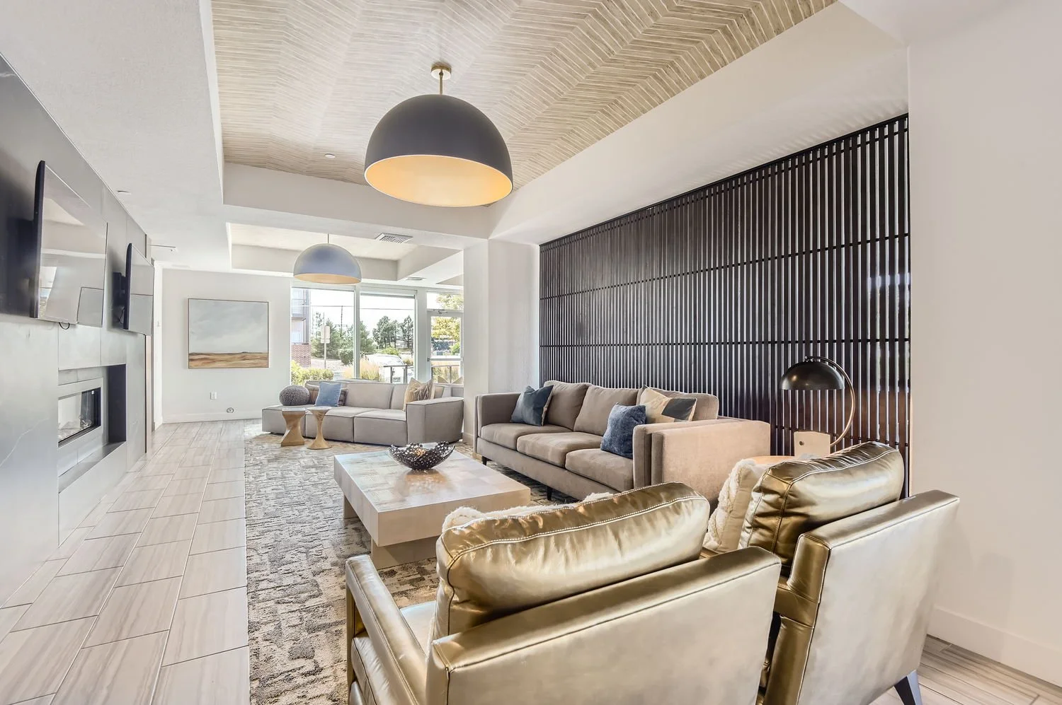 Modern living room with beige sofas, black wooden slat wall, large window, two black pendant lights, and a mix of decorative pillows