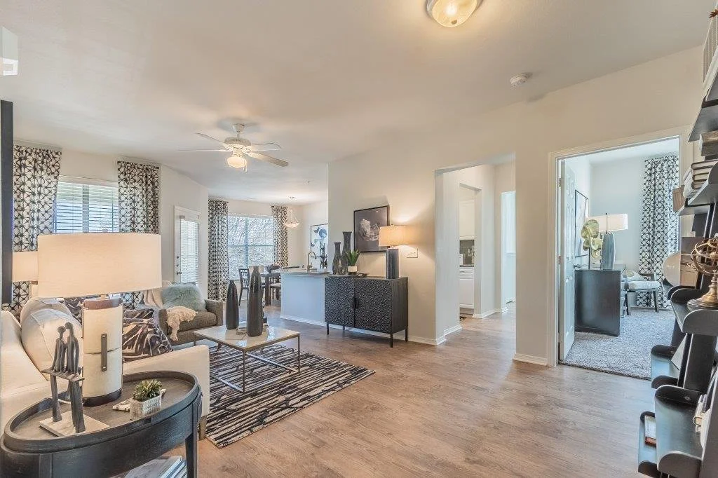 Open-concept living room and dining area with hardwood floors, furniture, curtains, and decor.