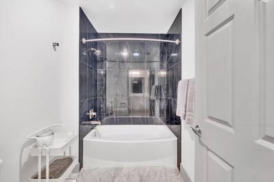 Bathroom with bathtub, glass shower enclosure, towel rack, and white walls.