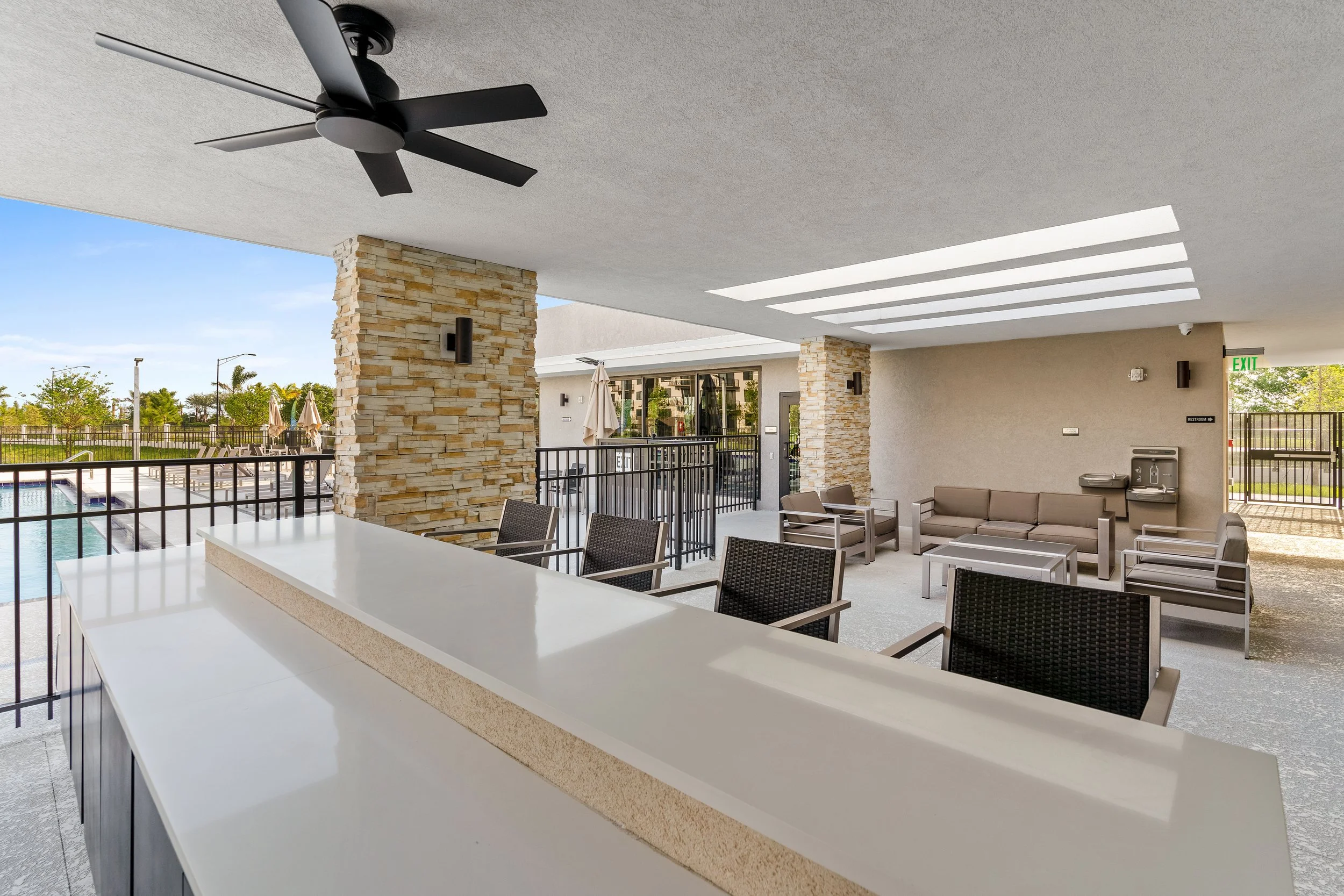 Indoor lounge area with seating, a water fountain, and a view of a pool outside.