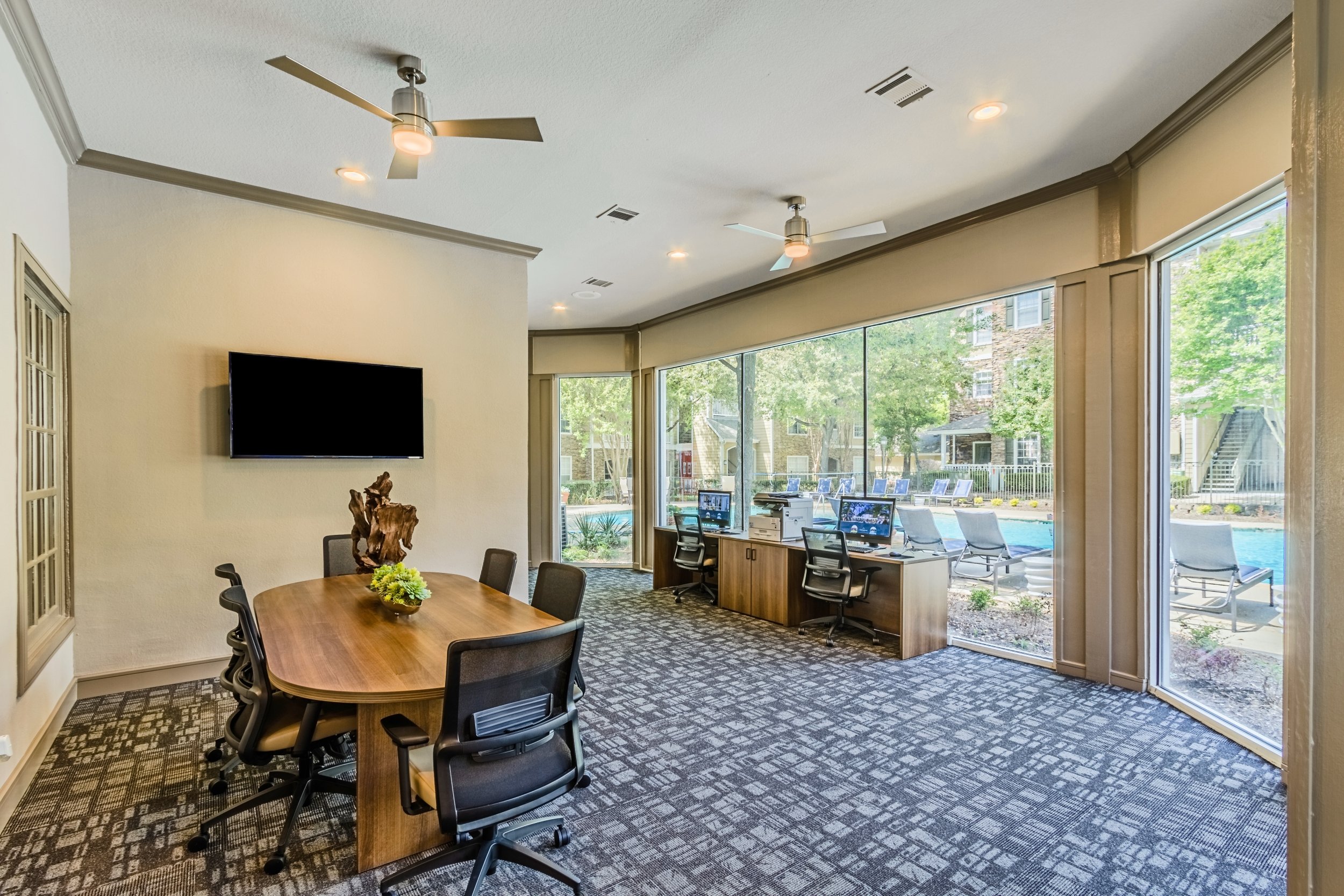 Interior of a modern meeting room with a large window overlooking a pool area.