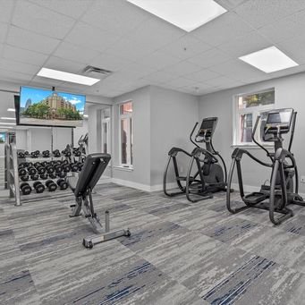 Fitness room with a flat-screen TV, free weights, exercise bike, and elliptical machine