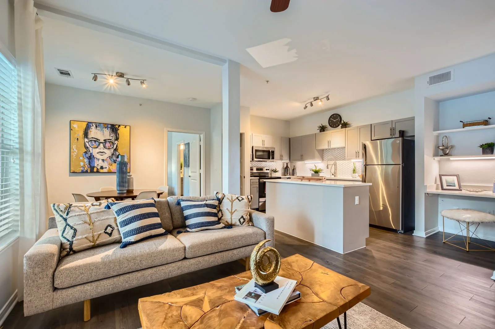 Open-concept living room and kitchen in a modern apartment with grey walls, hardwood floors, and contemporary furniture.
