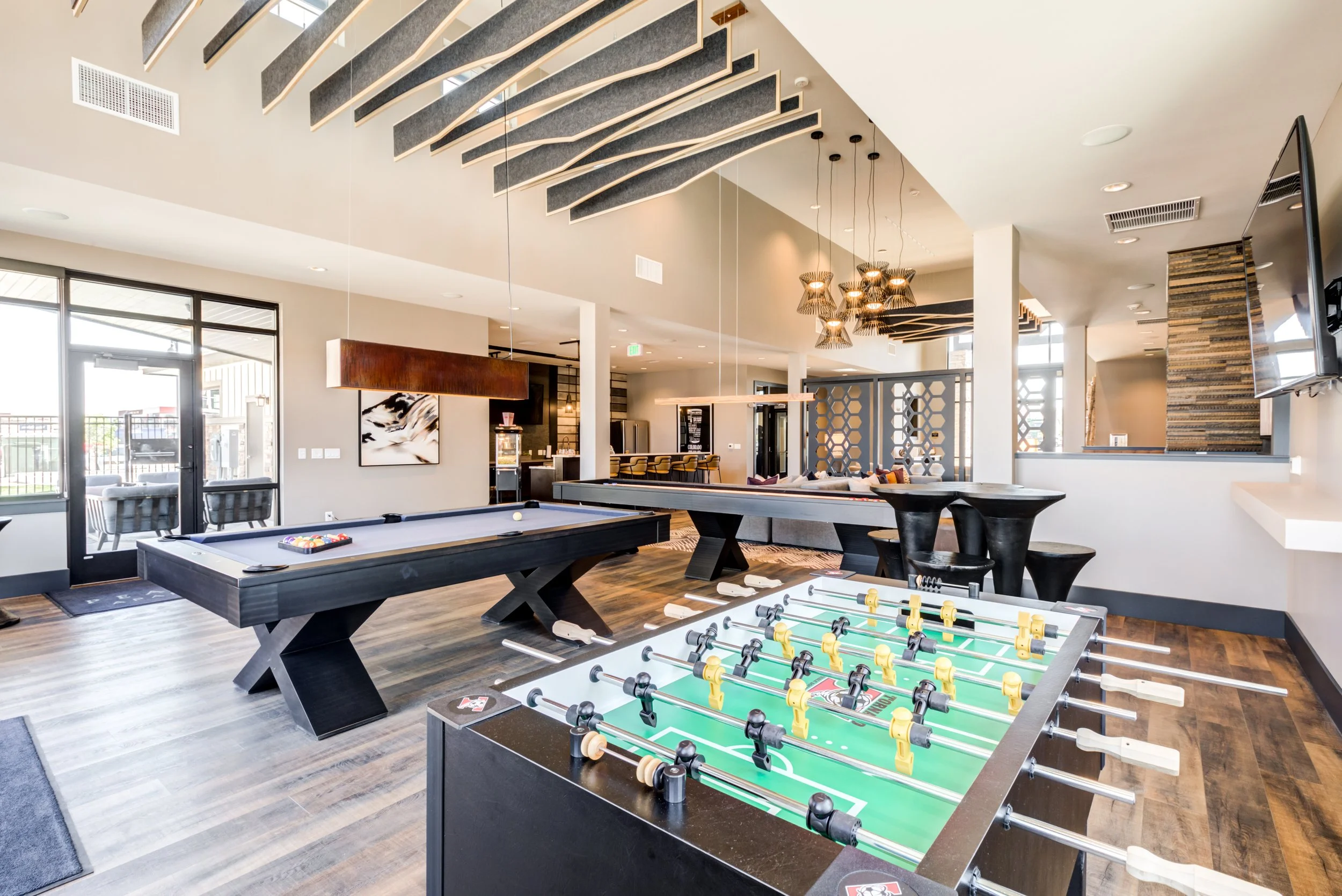 Interior of a recreational room featuring a foosball table, pool table, and seating area with modern decor.