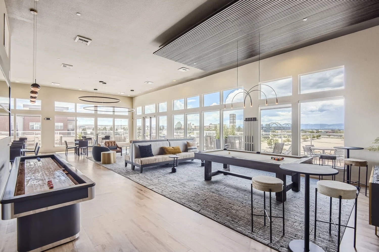 Bright lounge area with large windows, pool table, sitting chairs, and outdoor seating.