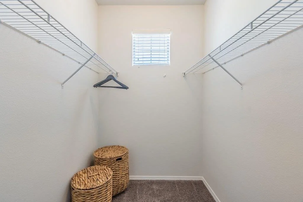 Empty walk-in closet with wire shelving, a small window, and woven baskets on the floor.
