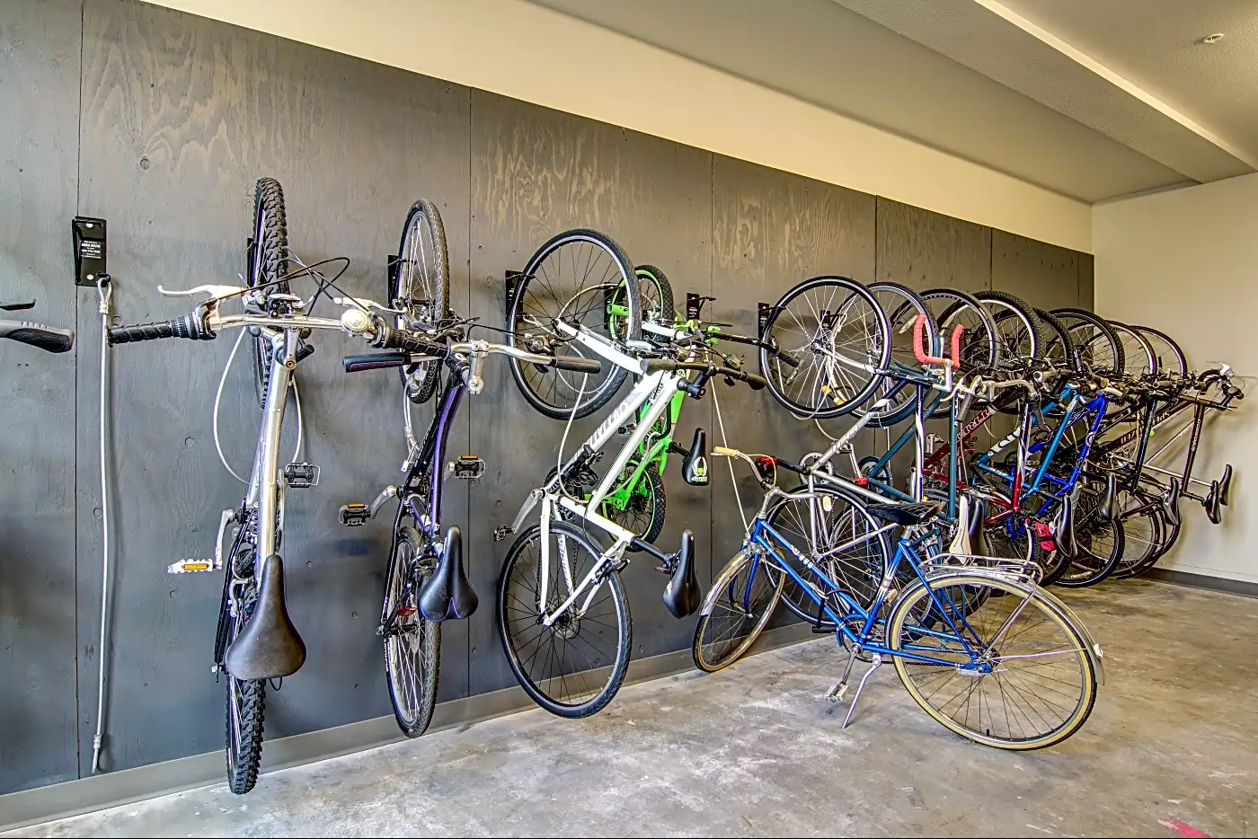 A row of bicycles stored on wall-mounted racks in an indoor bike storage room.