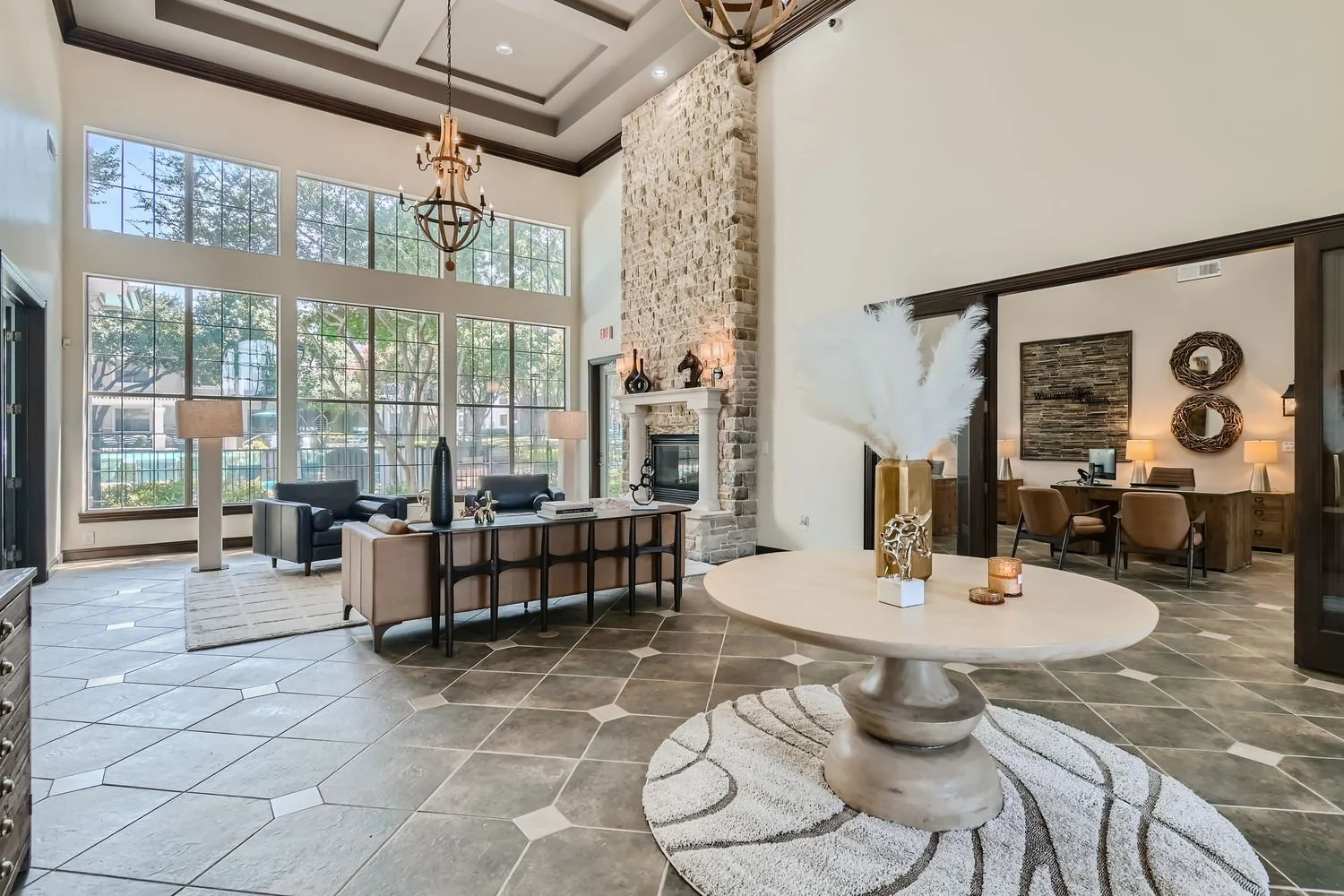 Interior of a modern lobby with large windows, a stone fireplace, and contemporary furniture, including a round table with a decorative vase and candles.