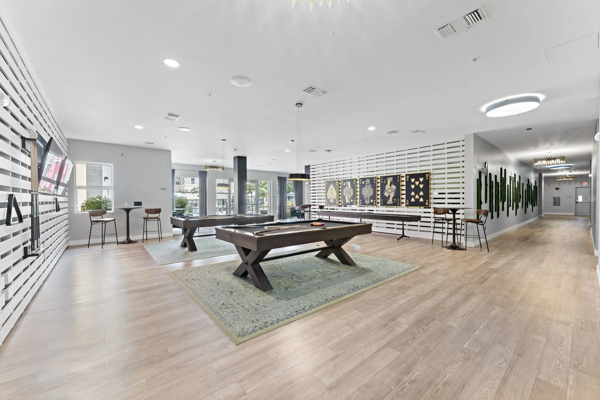 Bright, spacious recreation room with pool tables, artwork, chairs, and decorative wall features.
