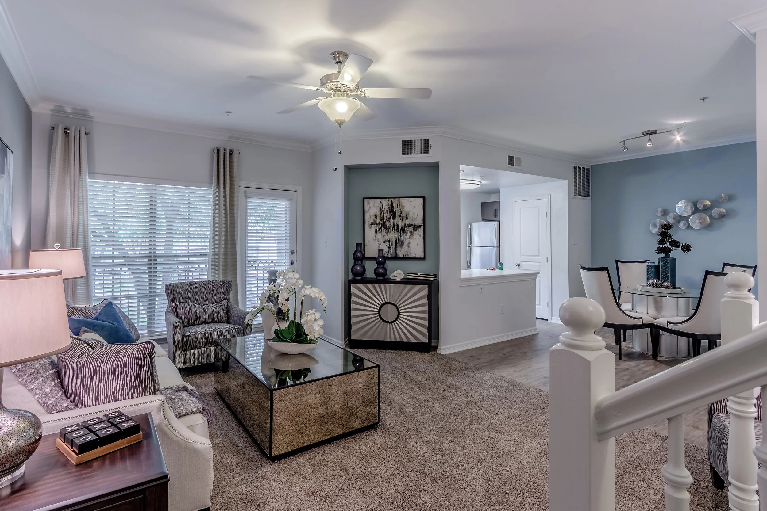 Living room with seating, coffee table, and decor, open to dining area and kitchen in background