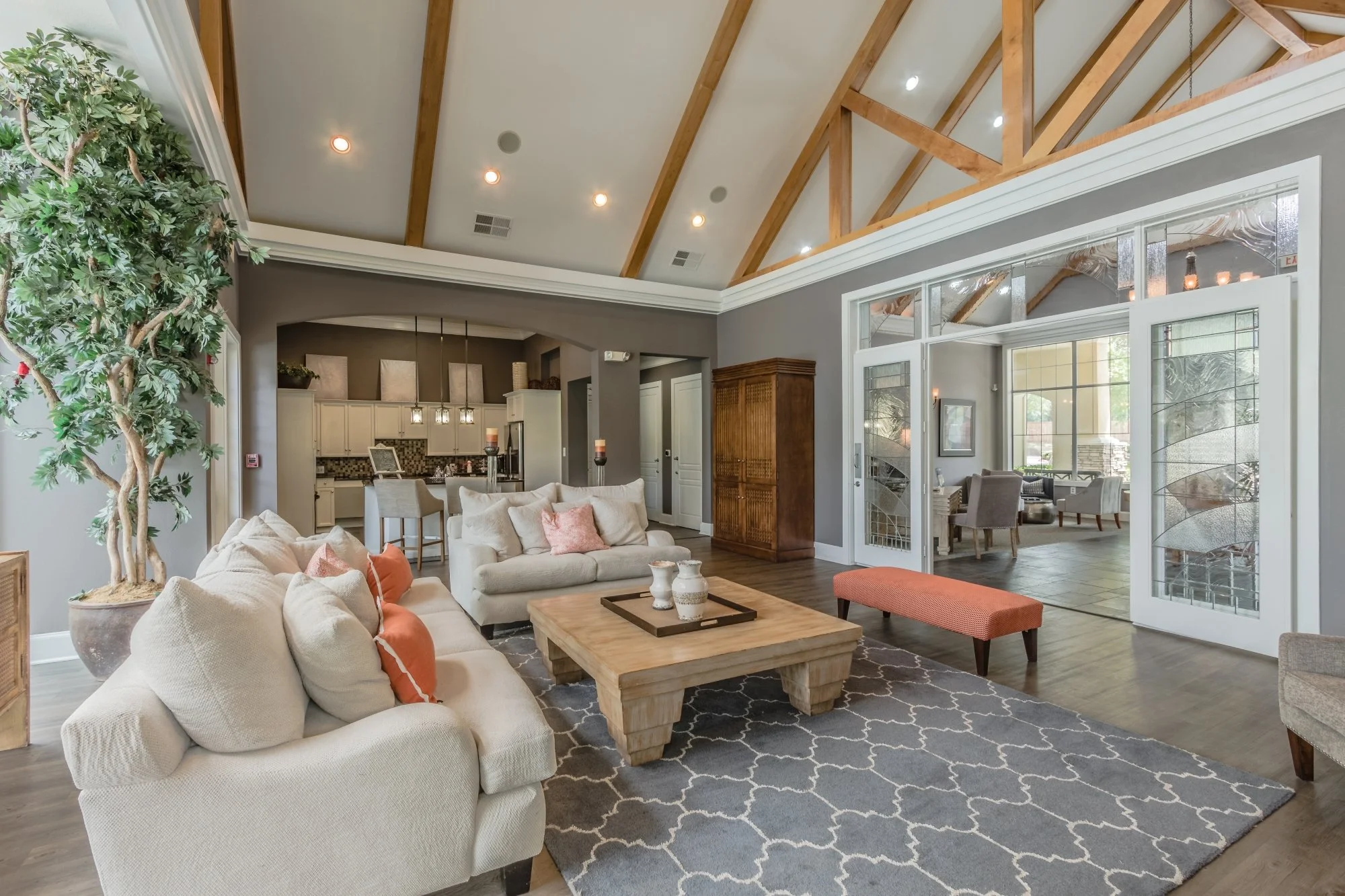 Living room with beige sofas, a wooden coffee table, a patterned rug, and large windows